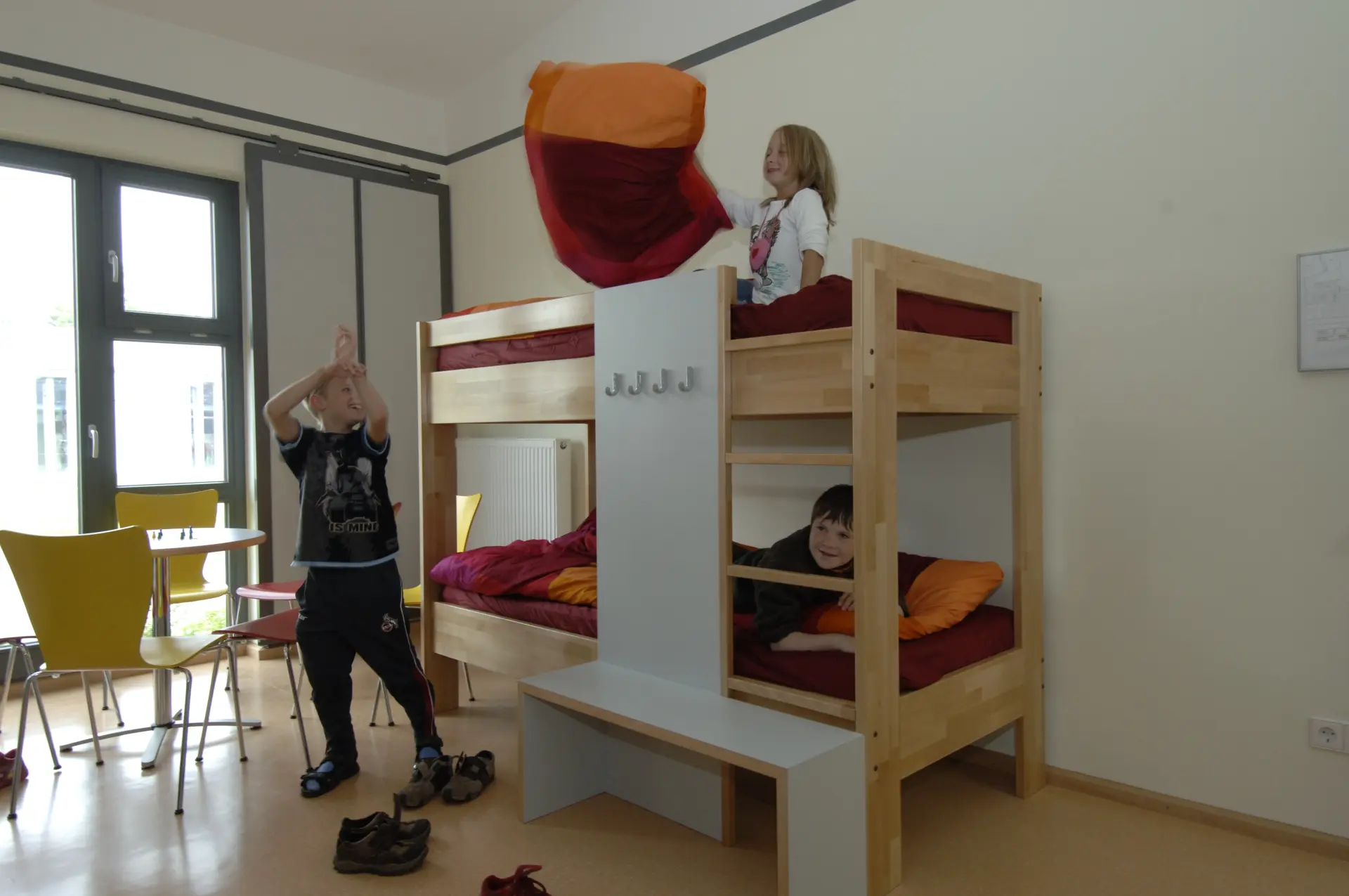Drei Kinder toben in und vor einem Stockbett.