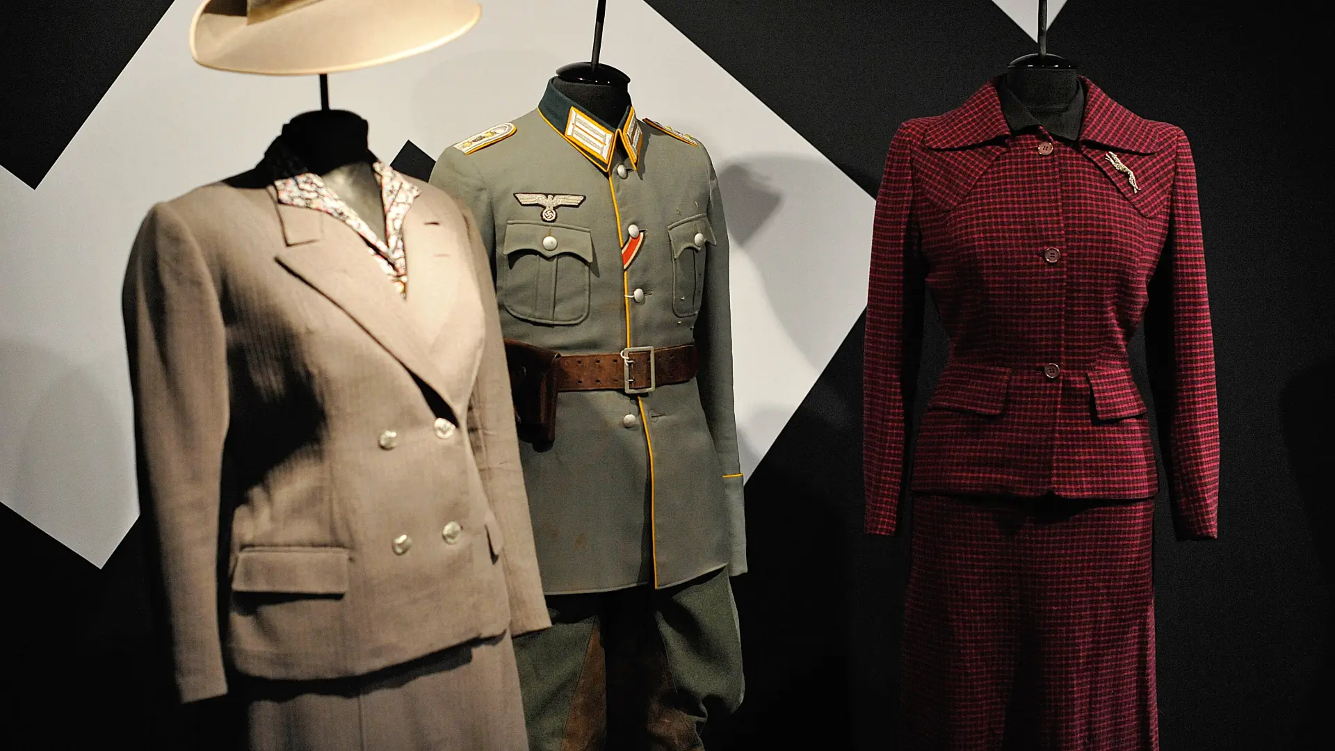 Eine Uniform und zwei Damen-Anzüge an Figurinen in einer Ausstellung