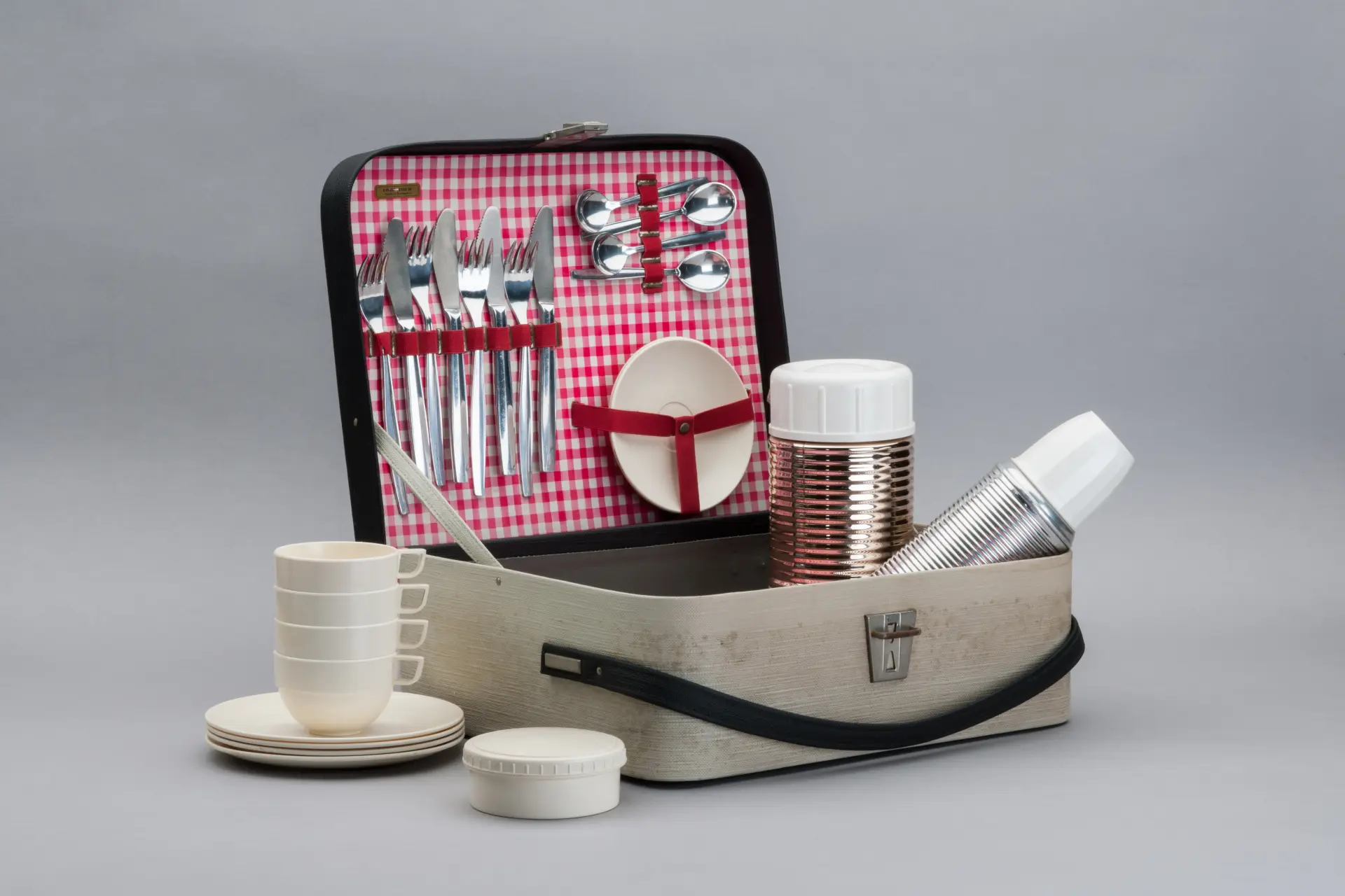 Ein geöffneter Picknickkoffer mit Besteck, Tellern, Tassen und Bechern