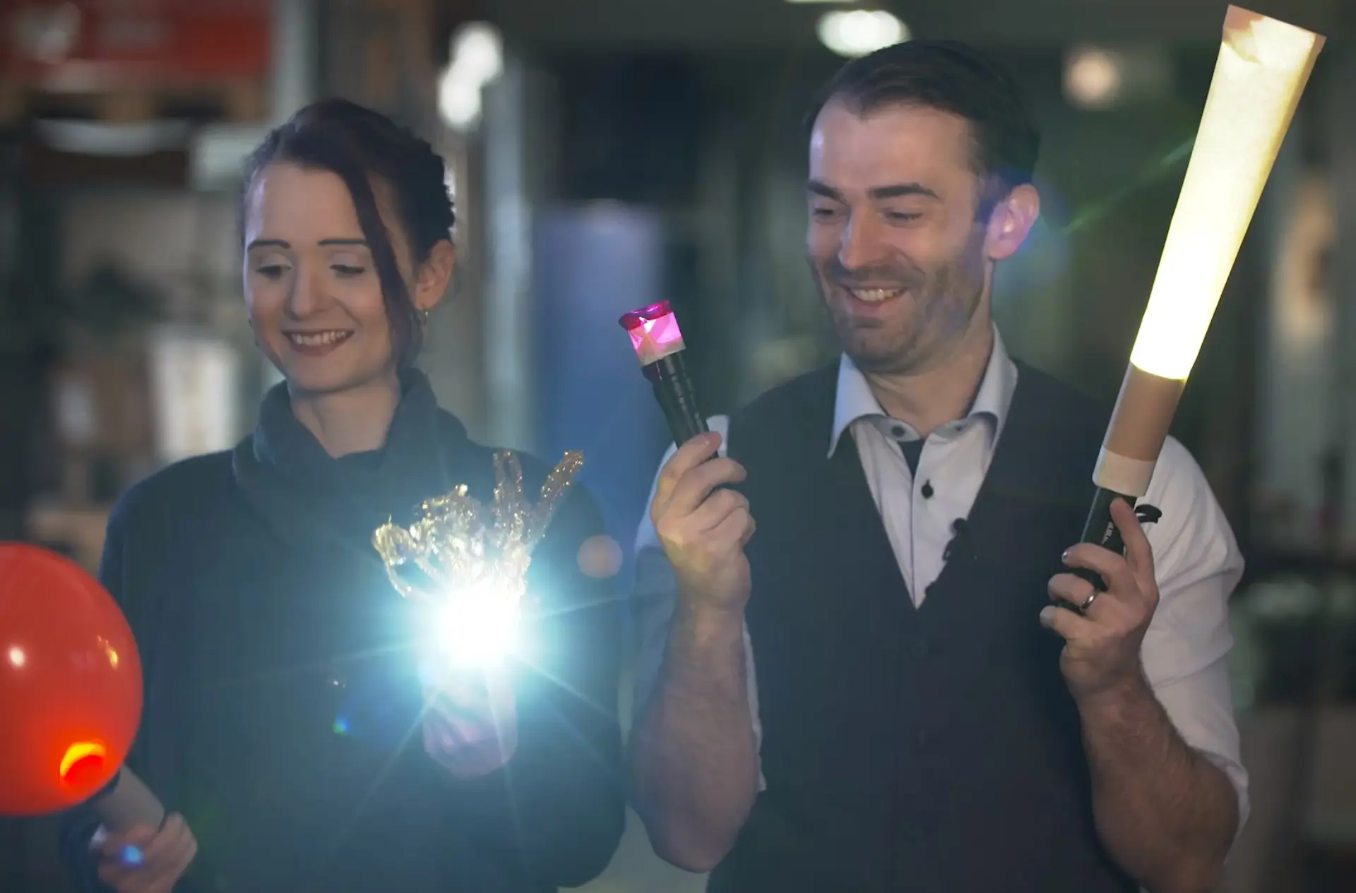 Ein Mann und eine Frau halten mit Papier umwickelte Taschenlampen.