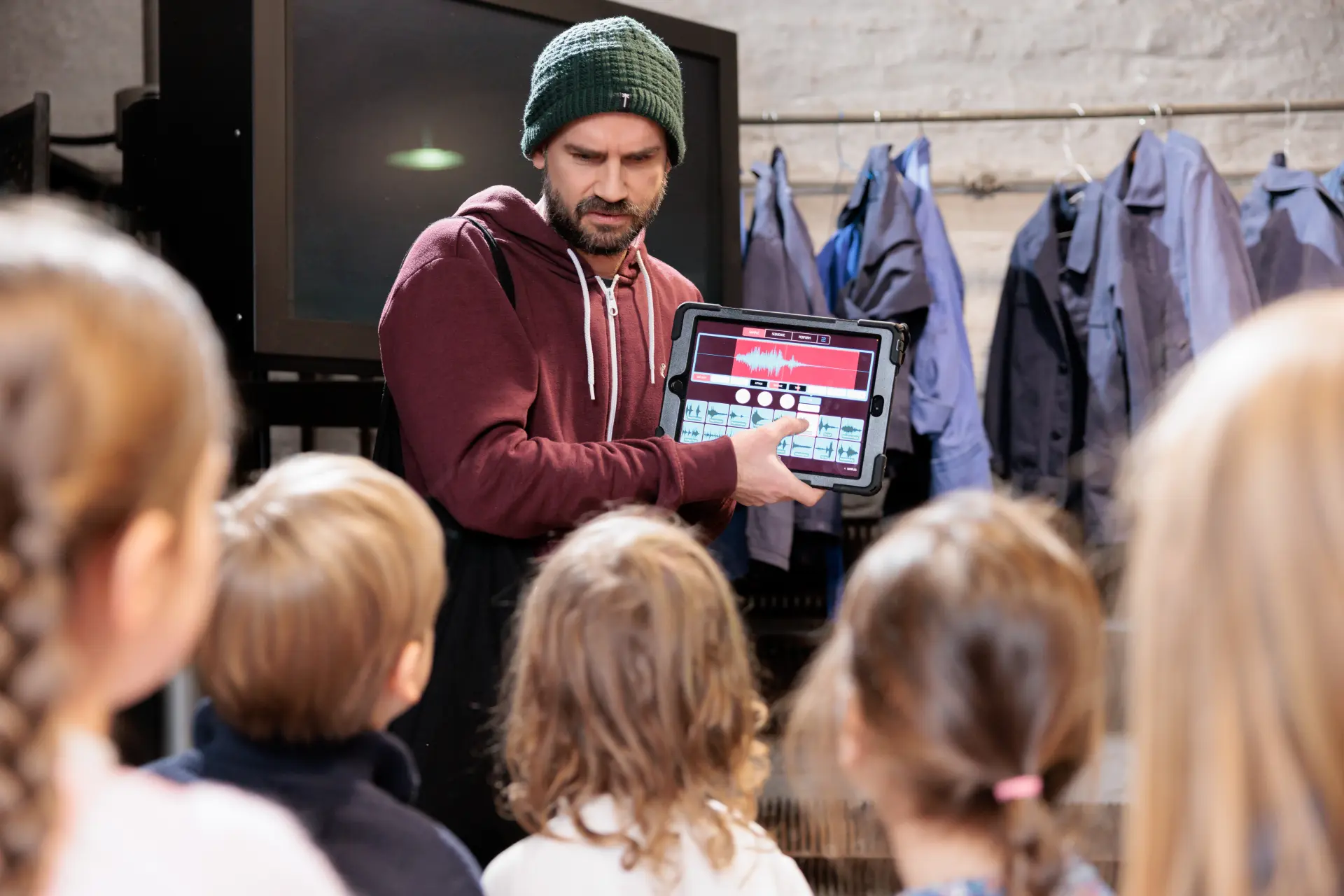 Ein Mann zeigt einer Gruppe von Kindern ein Programm auf einem Tablet.