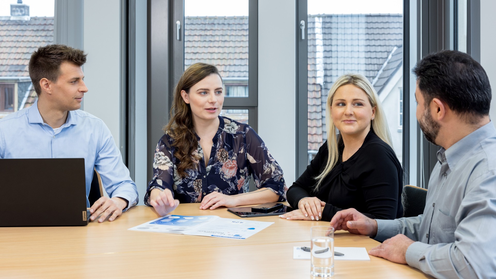 Vier Personen sitzen an einem Tisch und unterhalten sich