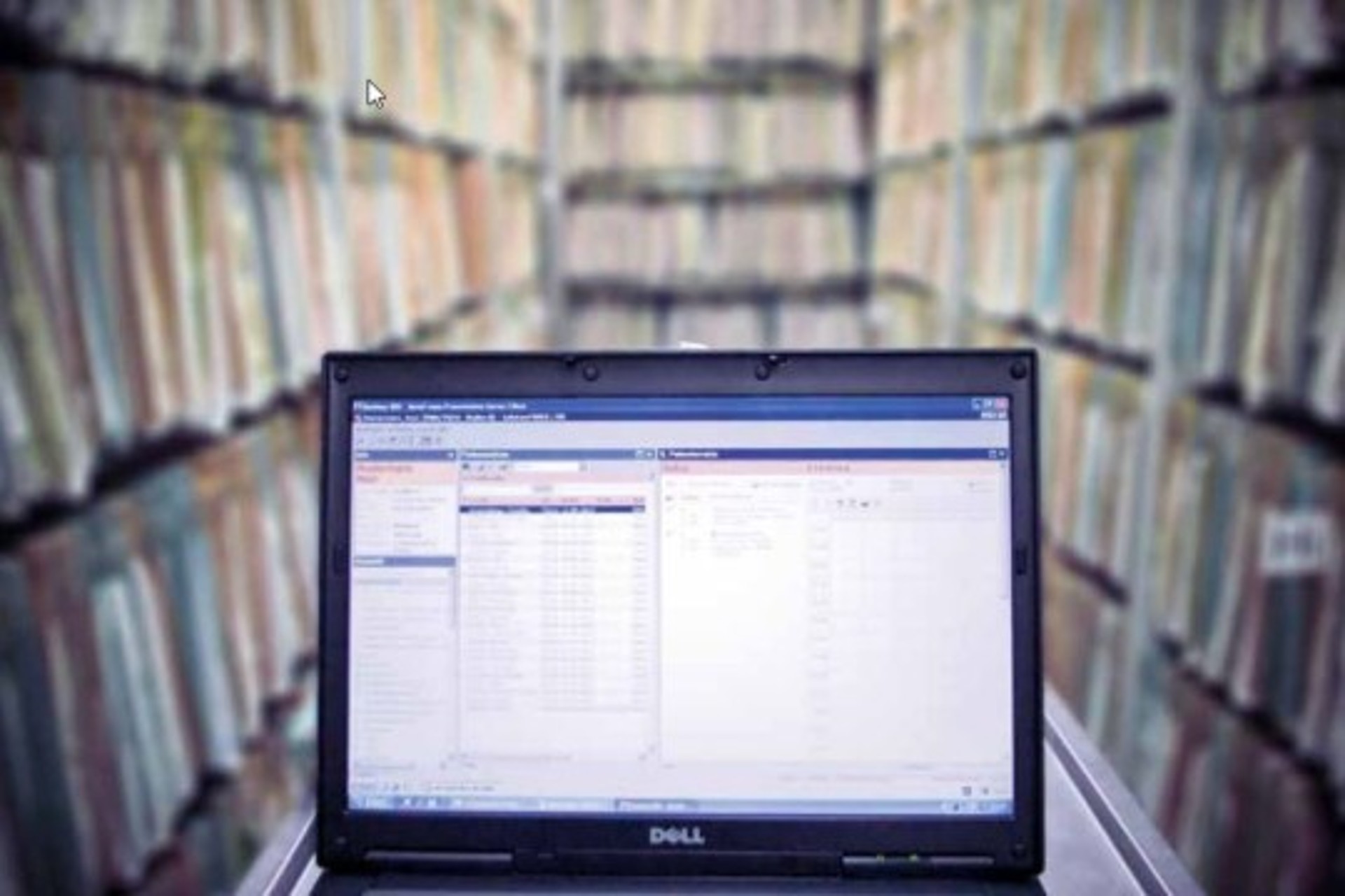 Laptop in einem Gang voller Papierakten