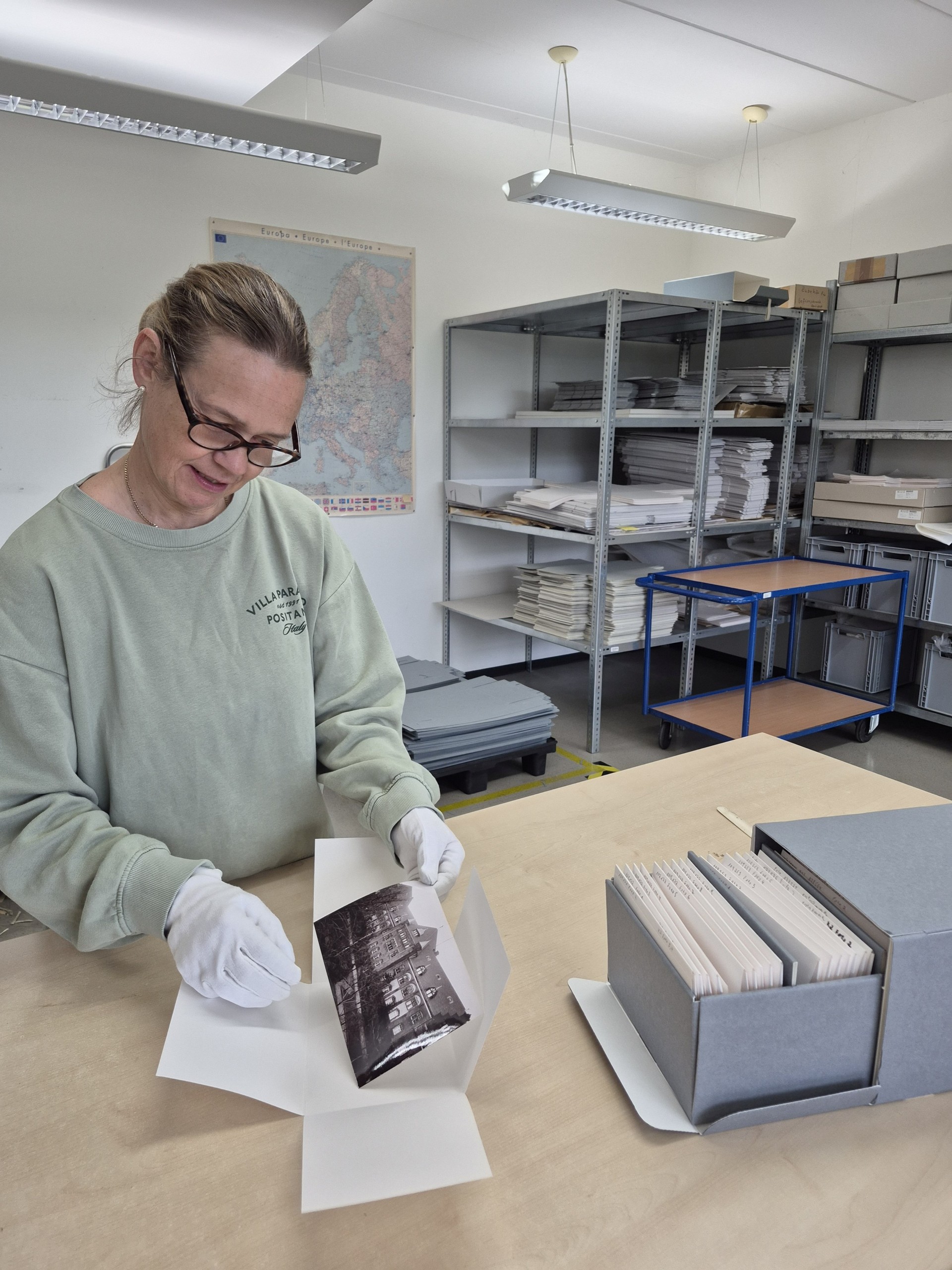Eine Frau steht an einem Tisch und verpackt ein historisches Foto.