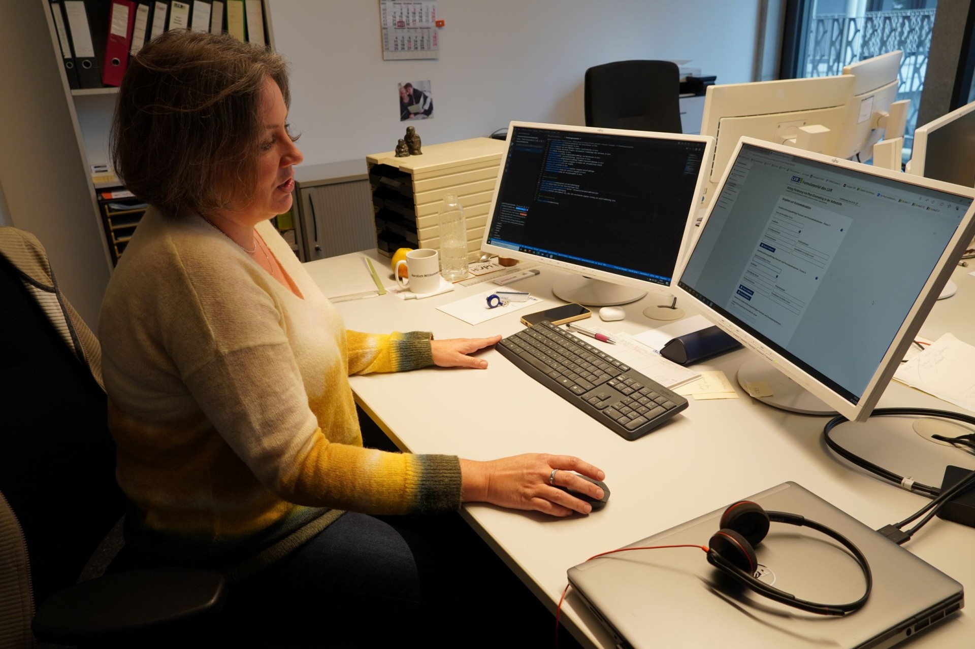 Eine Frau sitzt vor zwei Monitoren