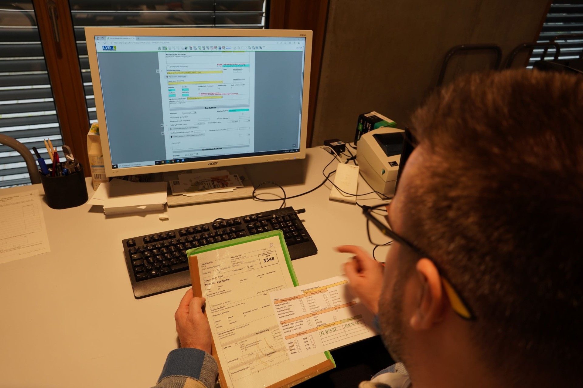 Ein Mann gleicht Daten auf dem Computer mit Daten auf Zetteln ab