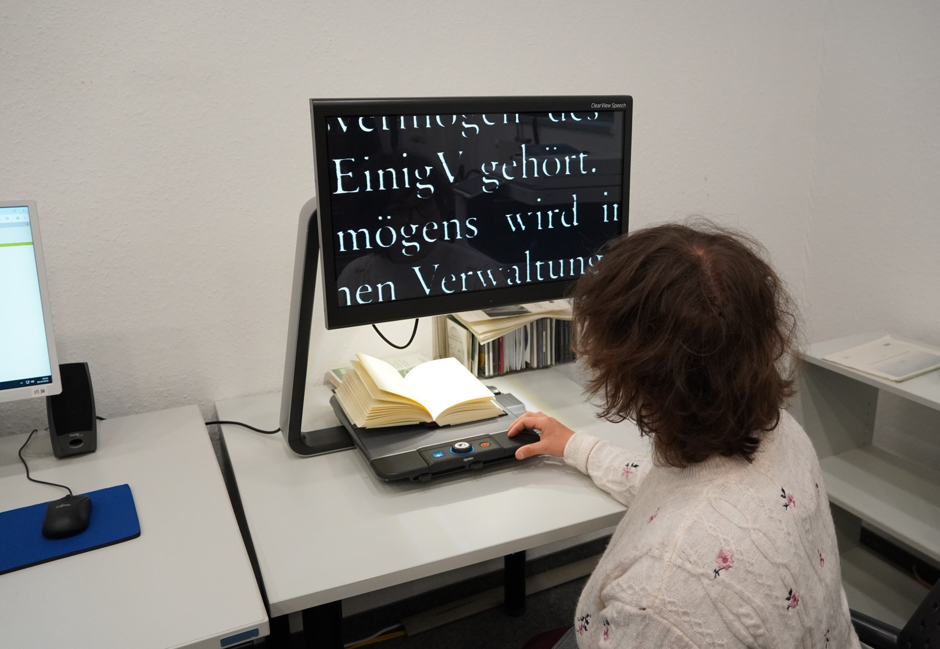 Eine Frau vor einem Bildschirmlesegerät mit stark vergrößertem Buchtext.
