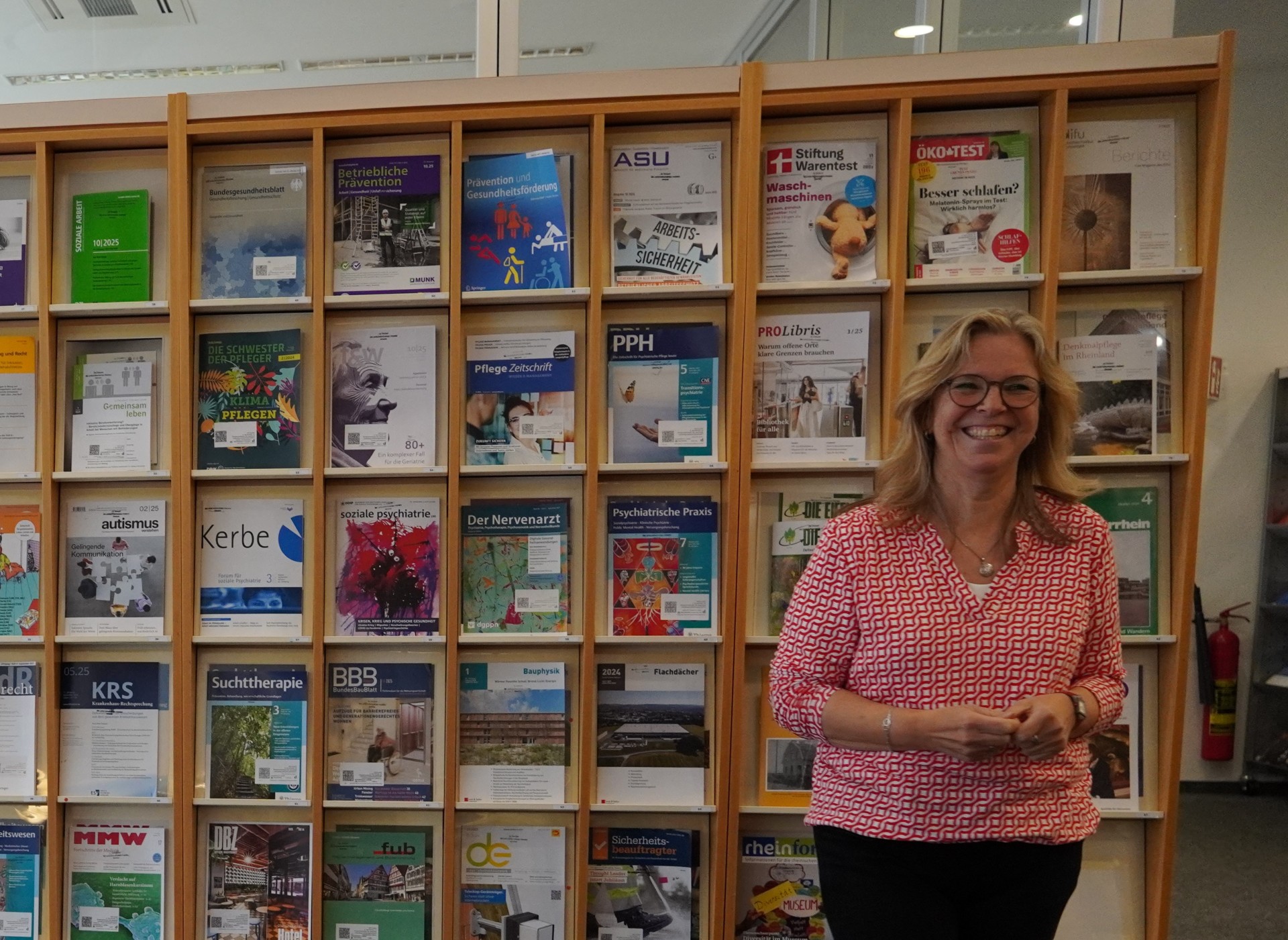 Anke Völzmann steht vor einem Zeitschriftenregal in der LVR-Bibliothek.