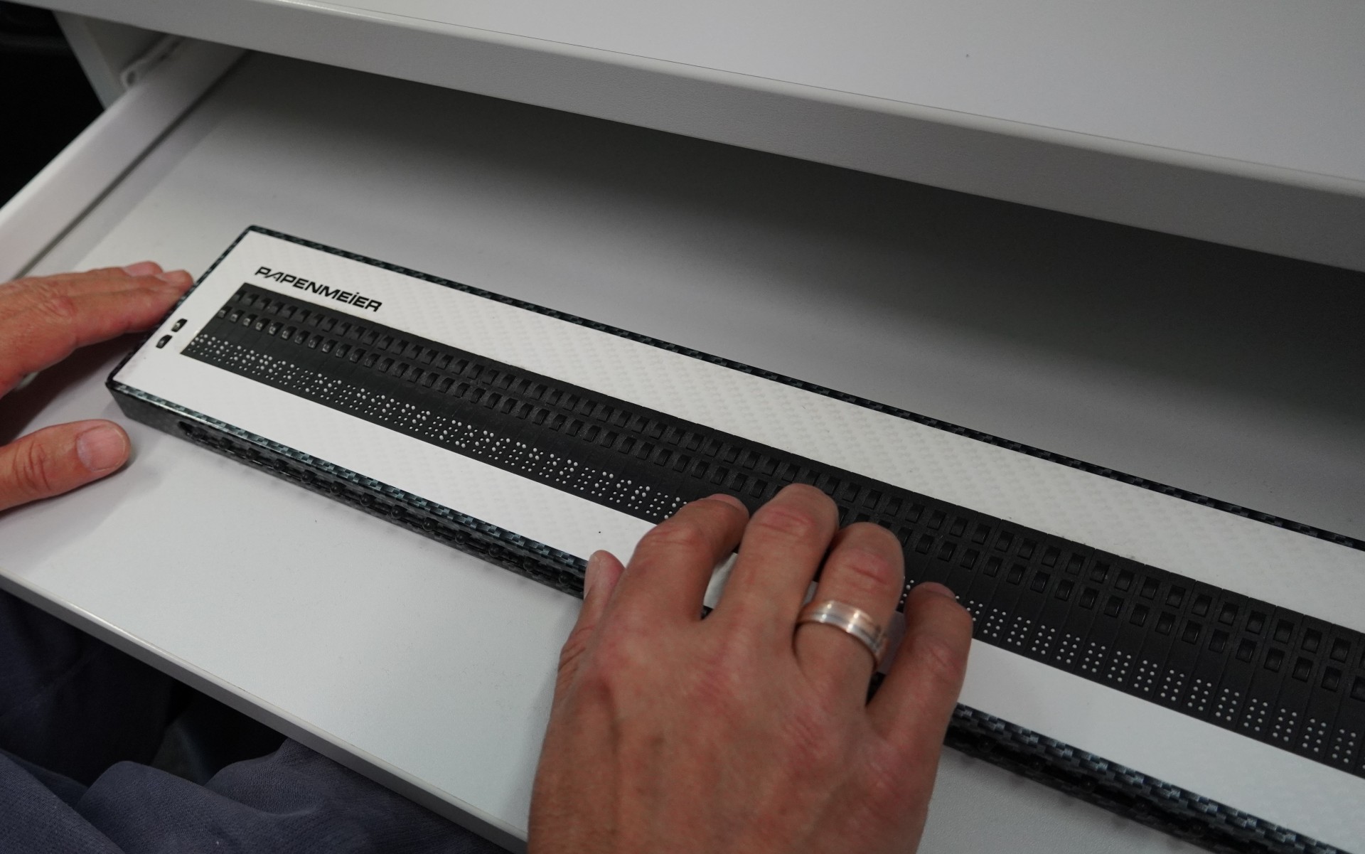 Eine Hand auf einer Braillezeile in Nahaufnahme