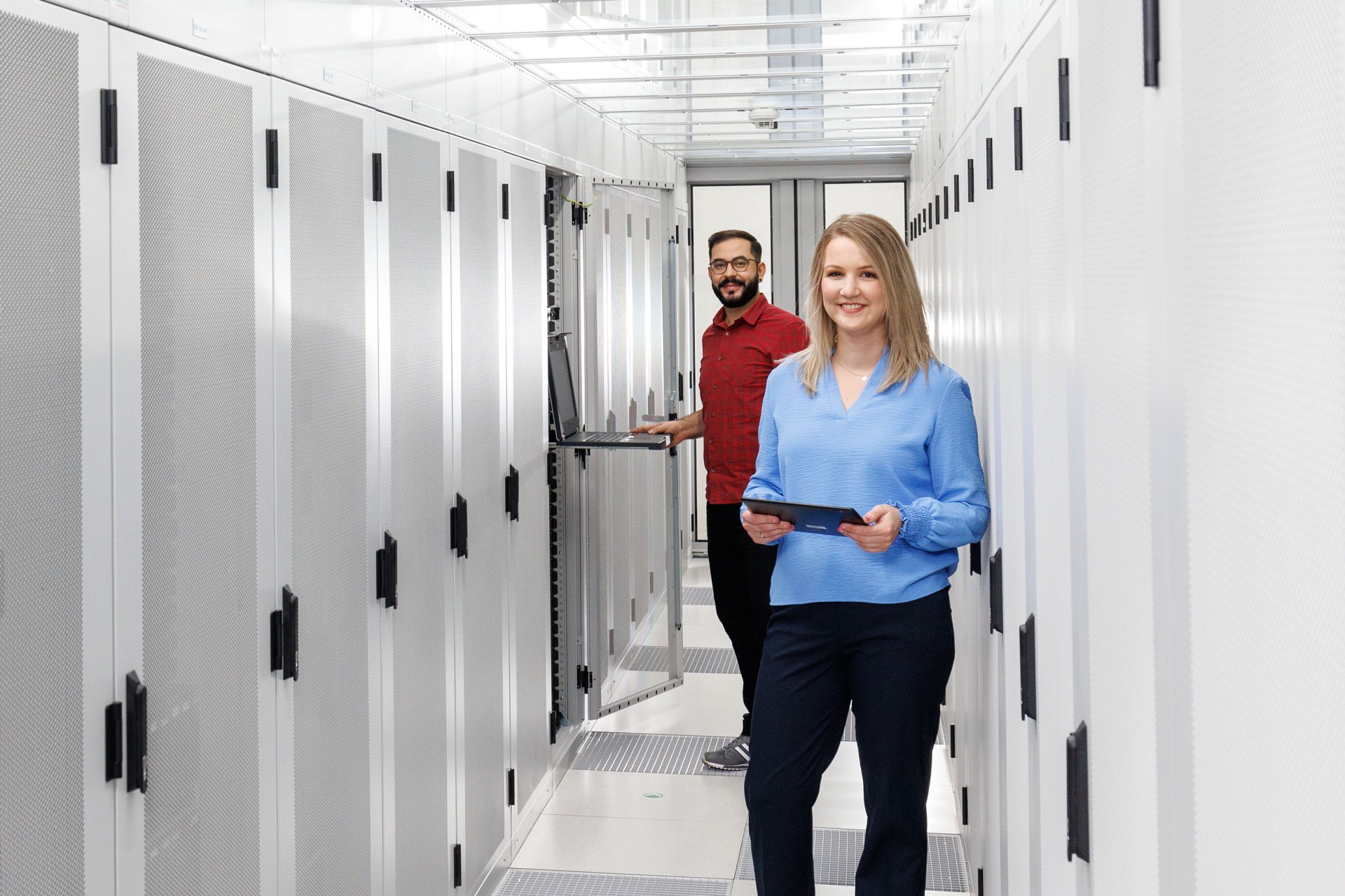 Eine Frau und ein Mann stehen im Gang zwischen Serverschränken