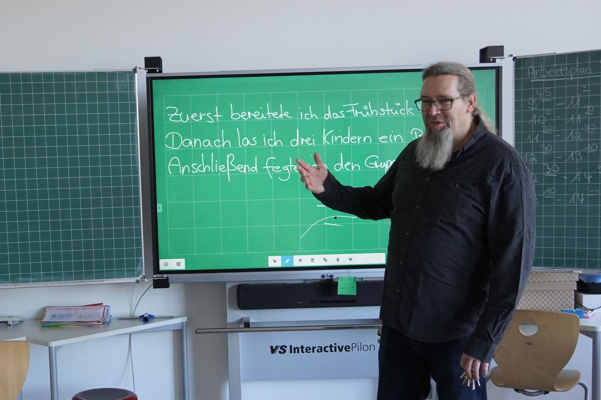 ein Lehrer steht vor einer digitalen Tafel