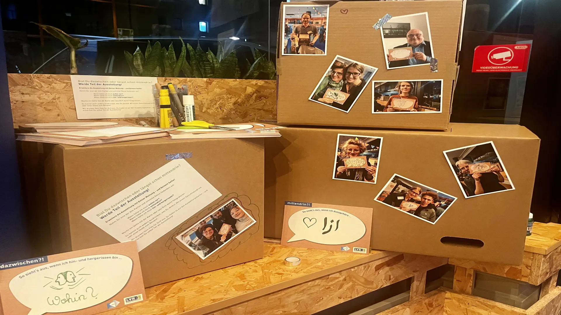 Kartons gestappelt. Auf den kartons sind Fotos und Zitate von Schüler*innen abgebildet.