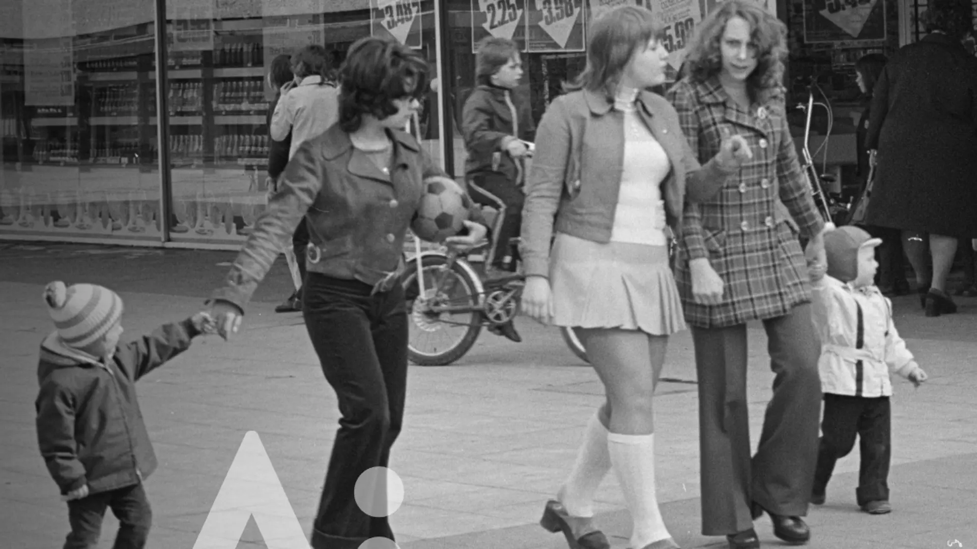 Vier  Personen gehen nebeneinander, zwei erwachsene Frauen in der Mitte, jeweils ein Kind links und rechts