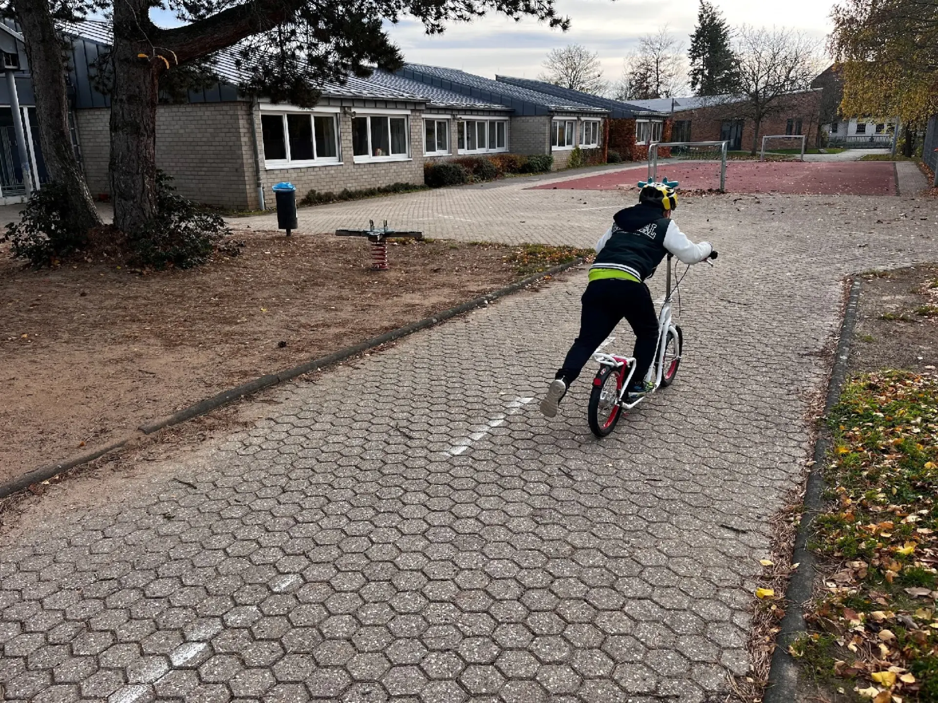 Kind fährt mit einem Roller auf dem Schulhof