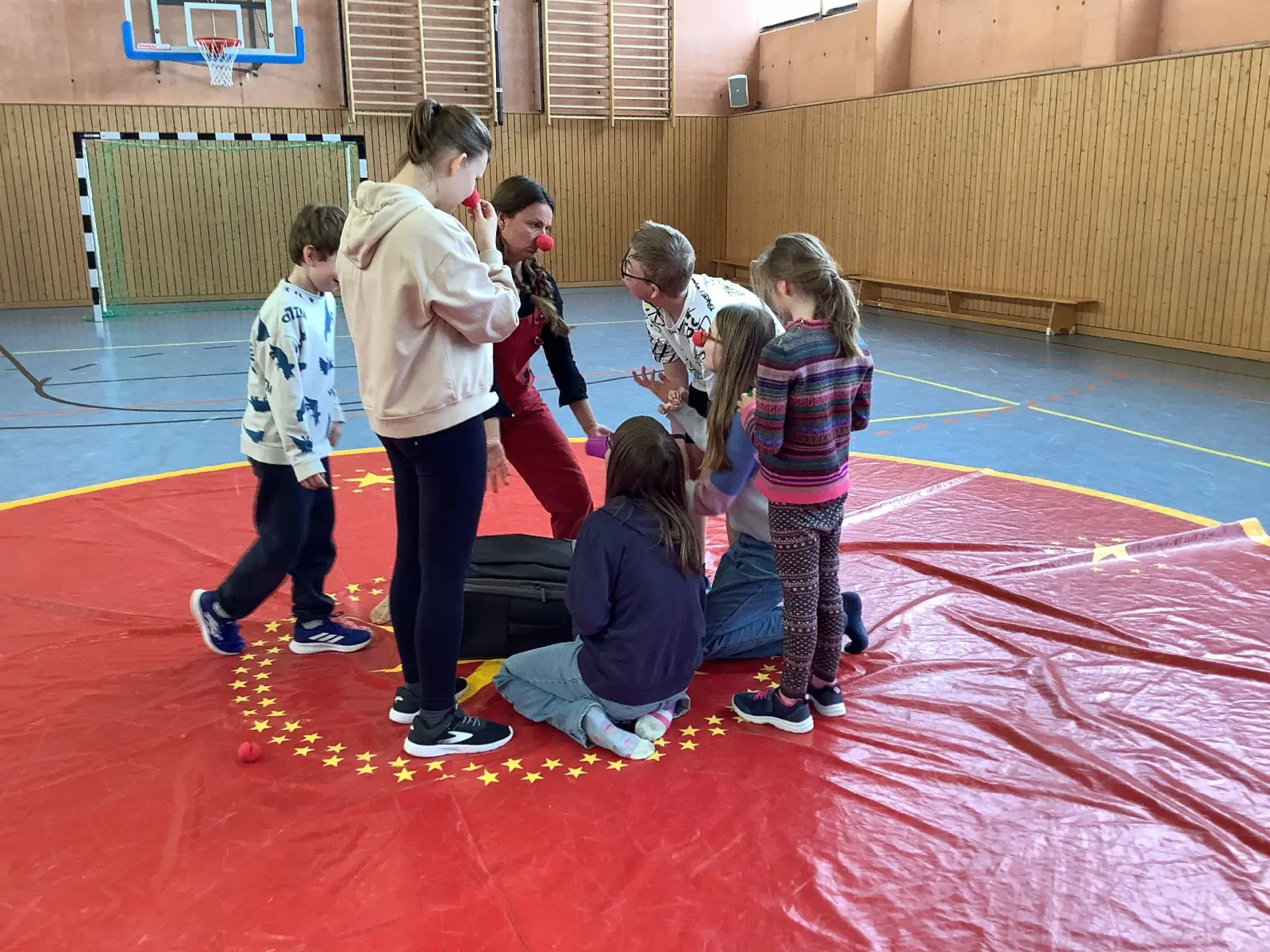 Kinder bei der Probe von Clown-Kunststücken in der Turnhalle