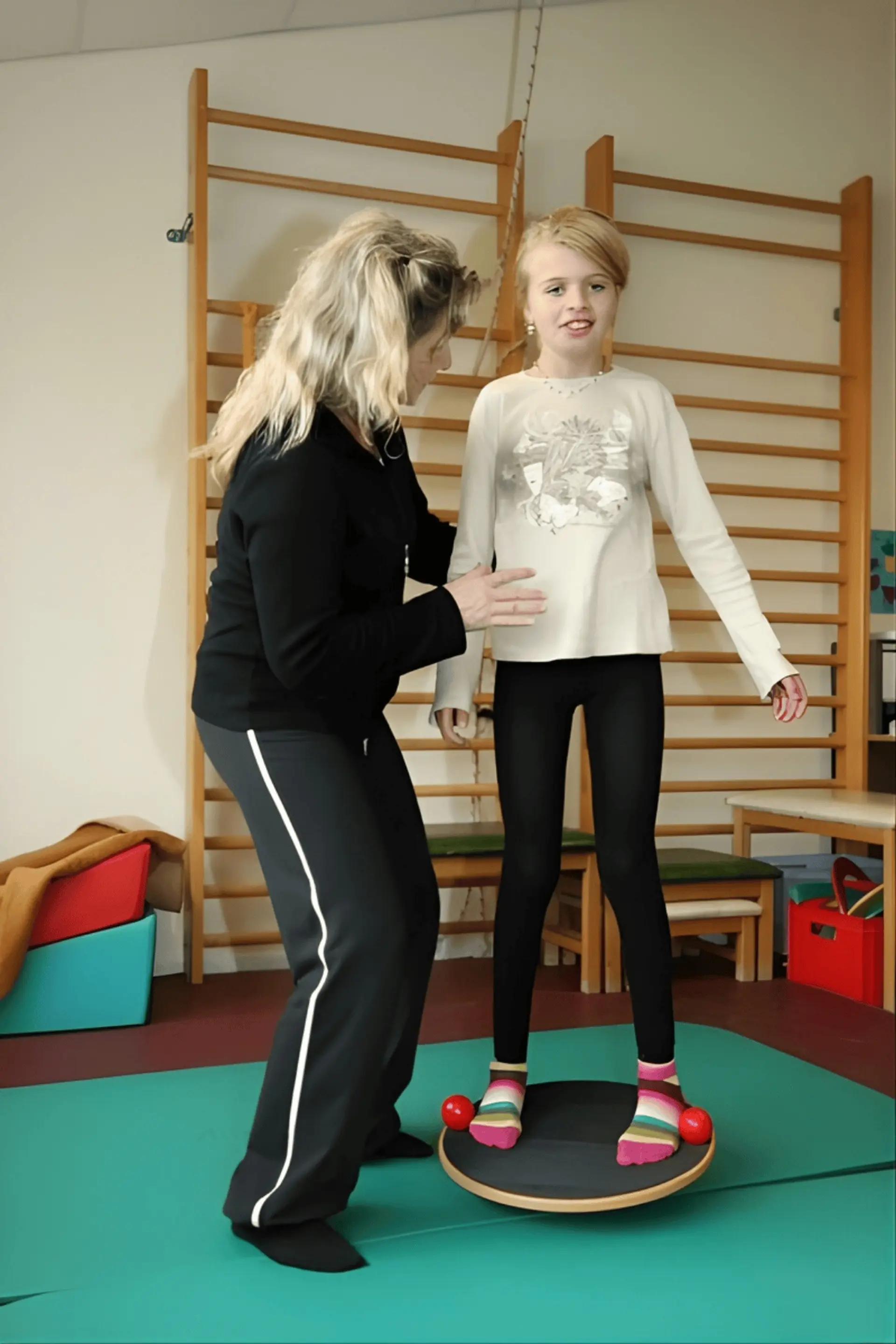 Physiotherapie: Kind steht in der Turnhalle auf einem Wackelbrett