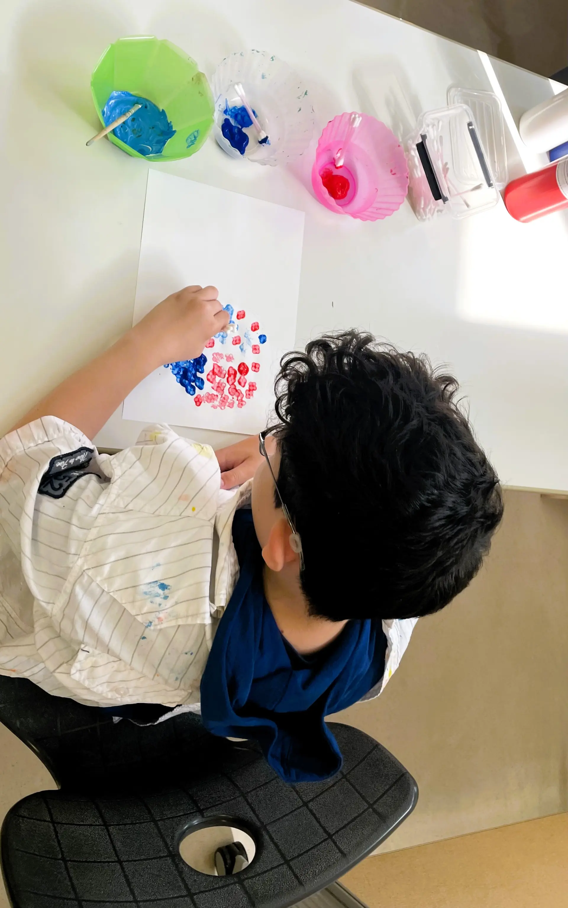 Schüler malt mit Wattestäbchen in der Ergotherapie