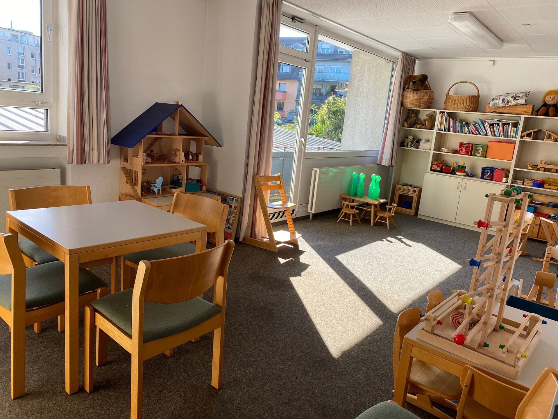Blick in den lichtdurchfluteten Raum der Beratungsstelle. Es gibt einen Tisch für Gespräche und Spielmaterial für Kinder. In den Regalen stehen weitere Materialien und Bücher.