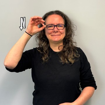 Profilfoto der Sekretärin für das Gemeinsame Lernen und die Frühförderung. Braune Locken, Brille und helle Haut. Der Gebärdenname ähnelt dem der Gebärde für "EULE".