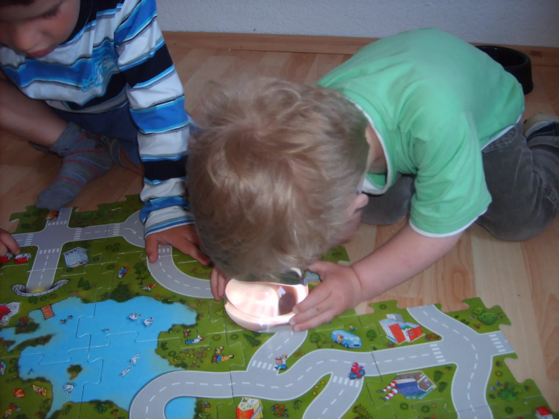 Junge schaut sich Straßenpuzzle mit der Lupe an