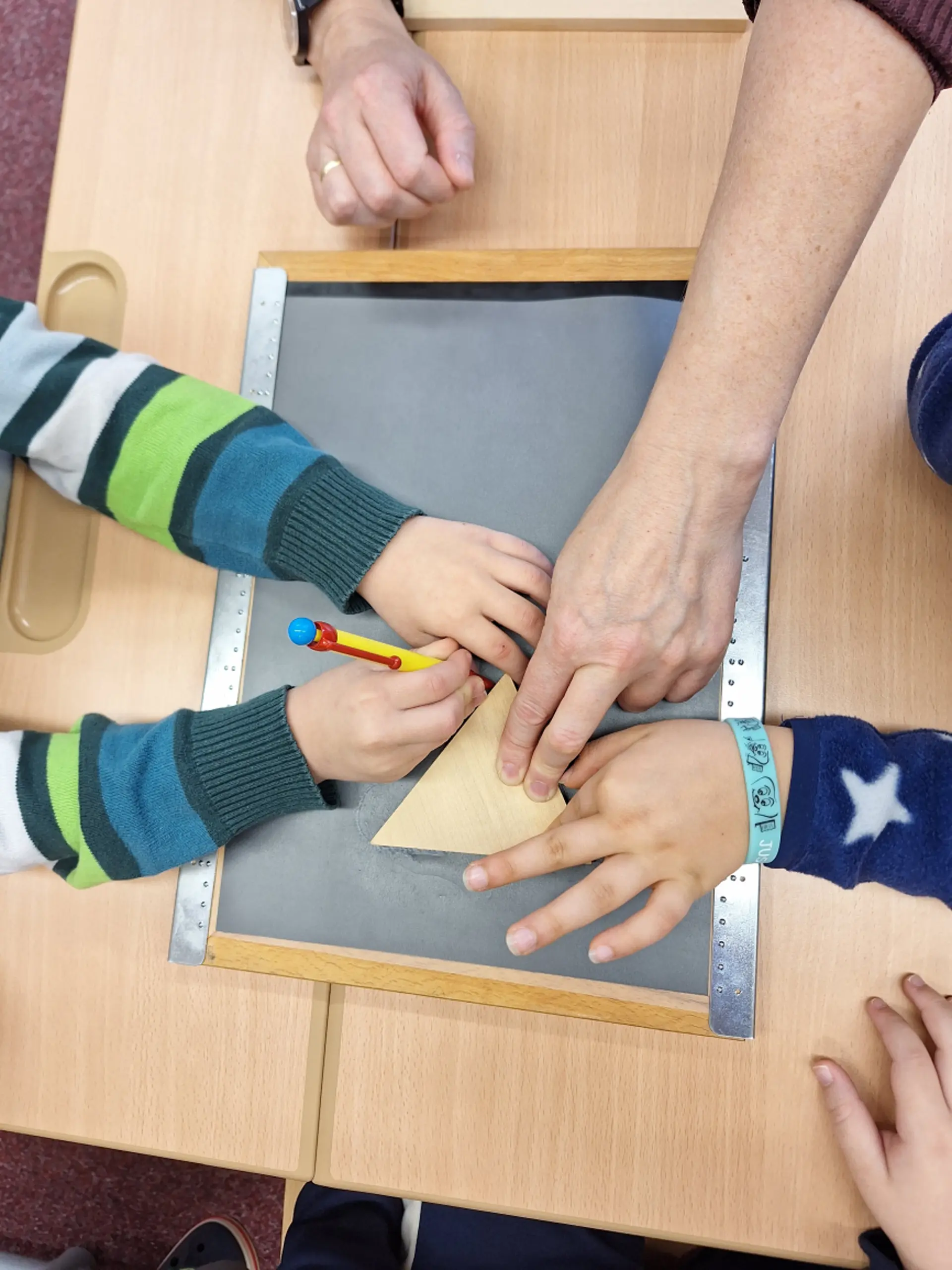 Geometrie: Kinder zeichnen Umrisse von einem Dreieck nach