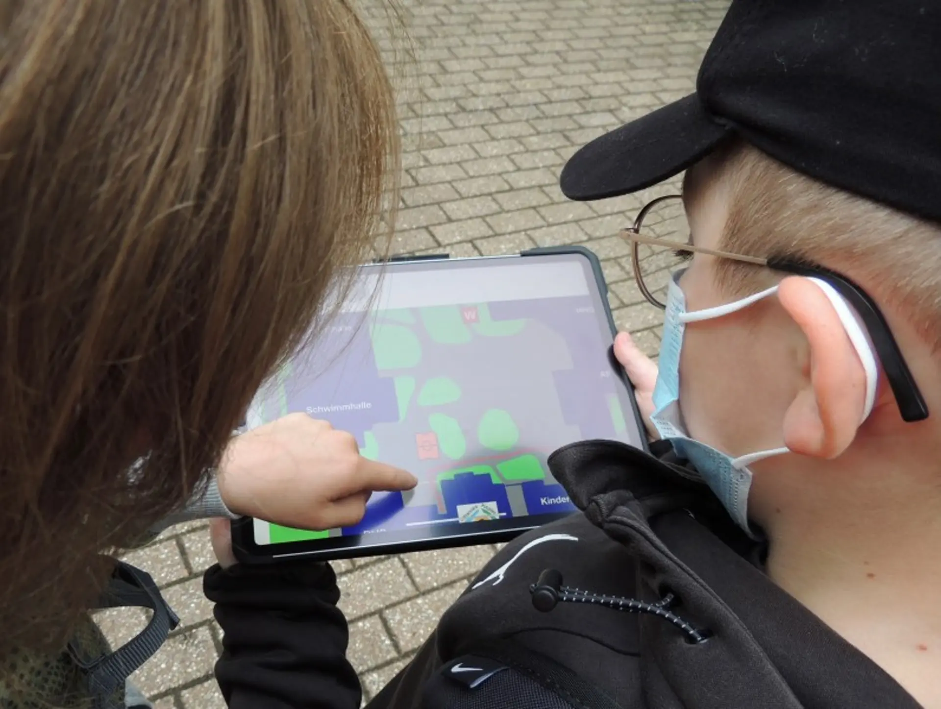 Kinder erkunden das Schulgelände mithilfe eines Tablets mit Vergrößerungsfunktion