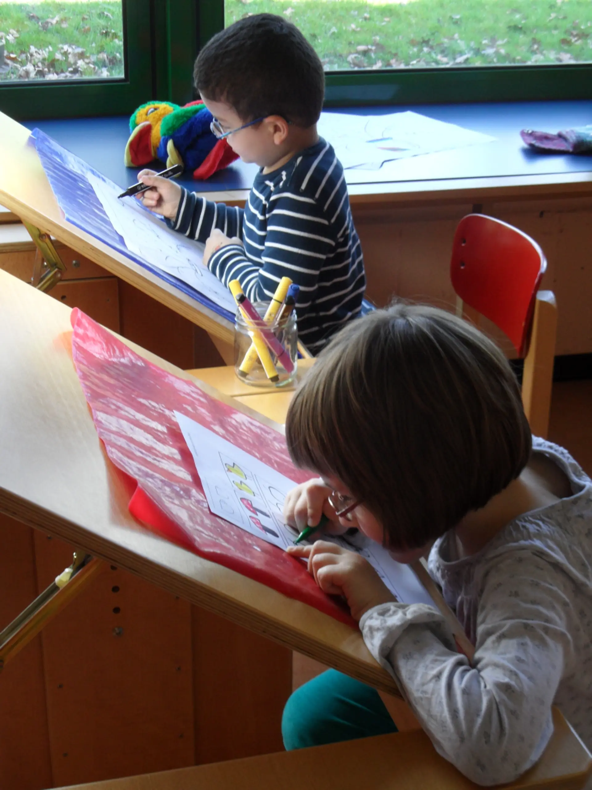 Kinder arbeiten an schrägen Tischen in der Vorschule