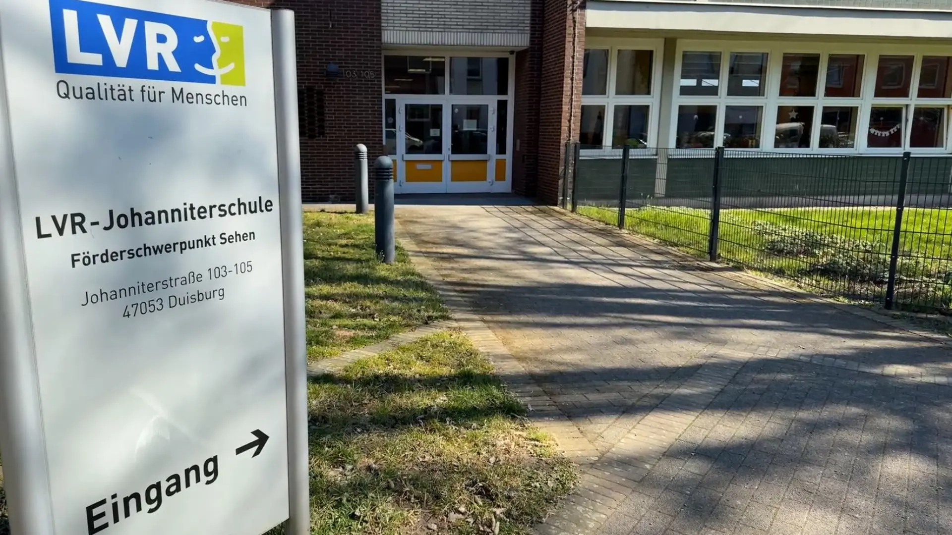 Eingangsbereich der LVR-Johanniterschule, im Vordergrund das Eingangssschild mit der Beschriftung: LVR-Johanniterschule, Förderschwerpunkt Sehen. Johanniterstraße 103–105, 47053 Duisburg