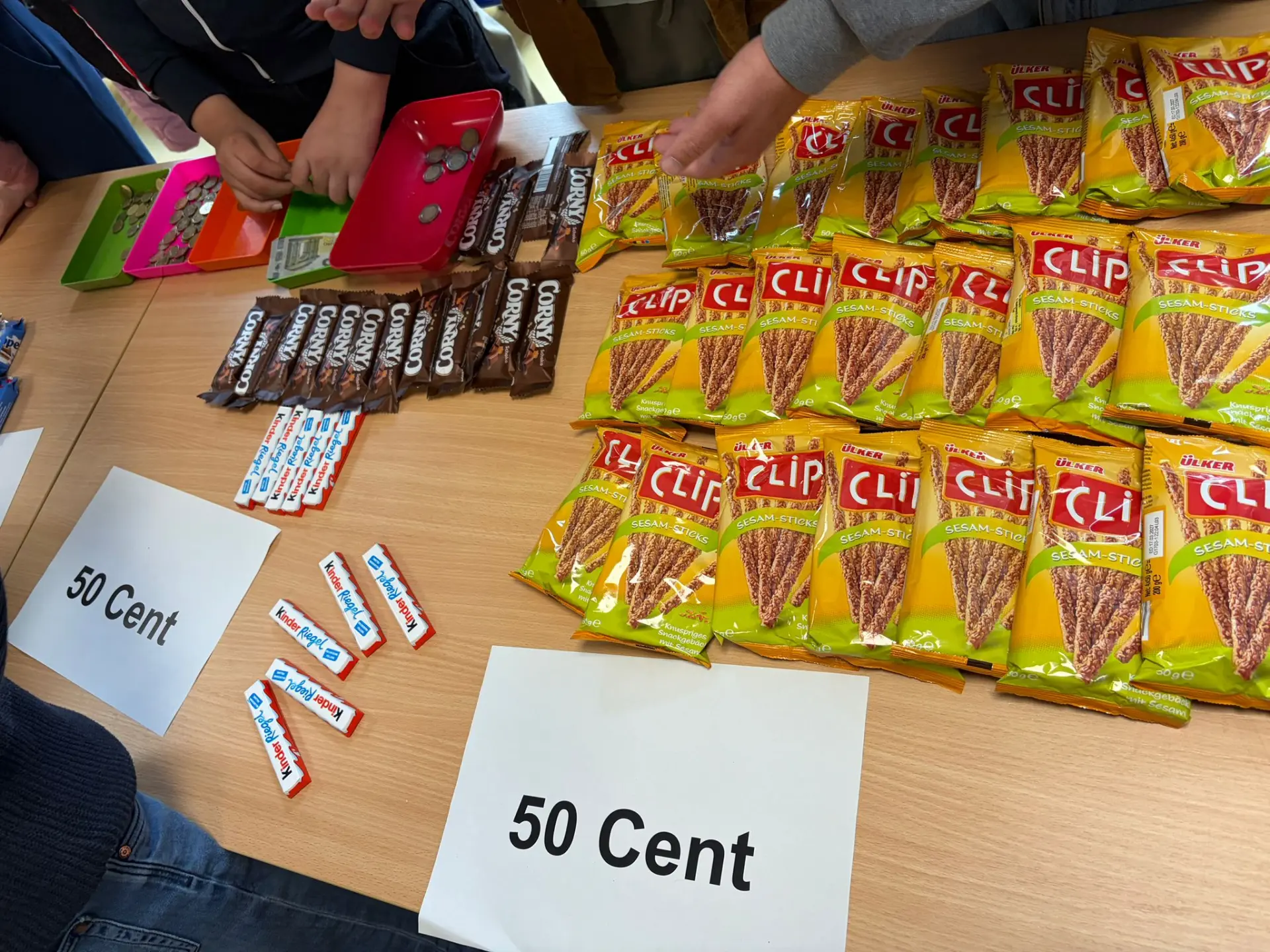 Auf einem Tisch befinden sich Snacks, Süßigkeiten, Schokolade und ein Preisschild, welches 50 Cent anzeigt