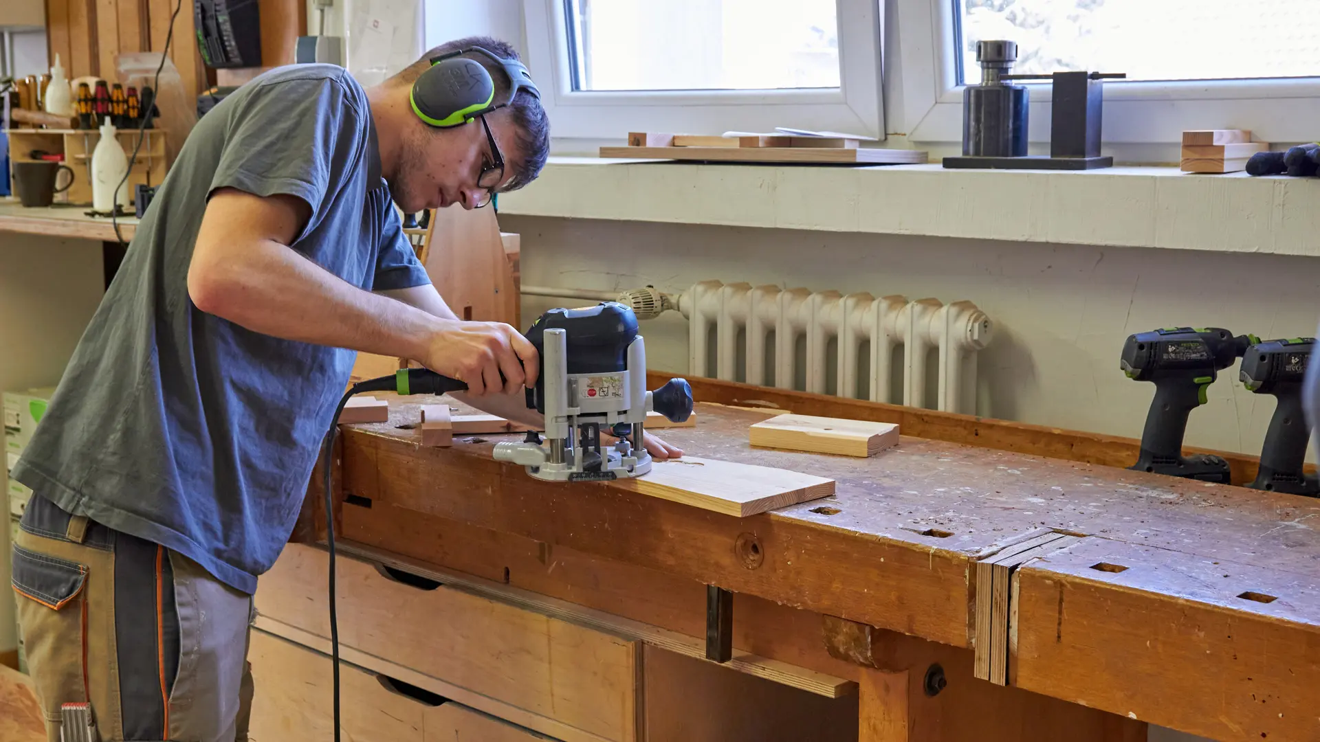 junger Mann bearbeitet ein Holzbrett an einer Werkbank
