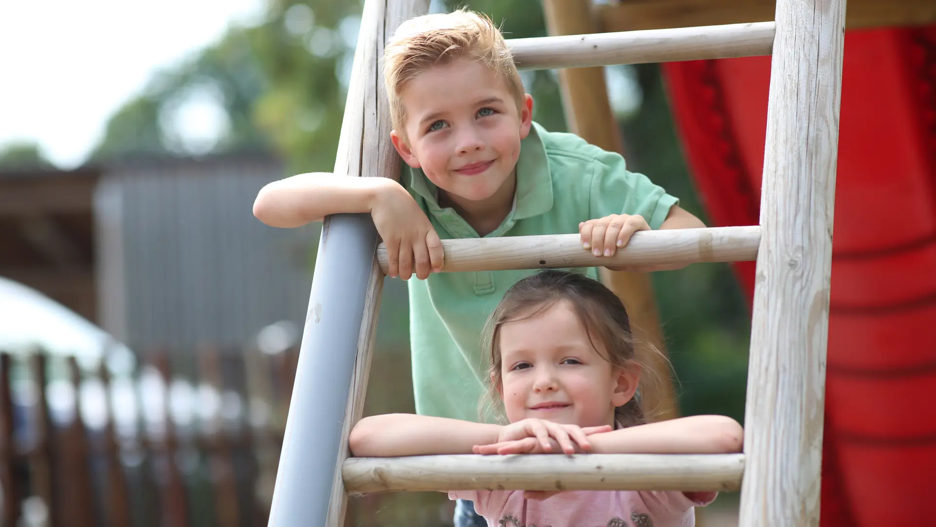 zwei Kleinkinder auf einer Spielplatzleiter