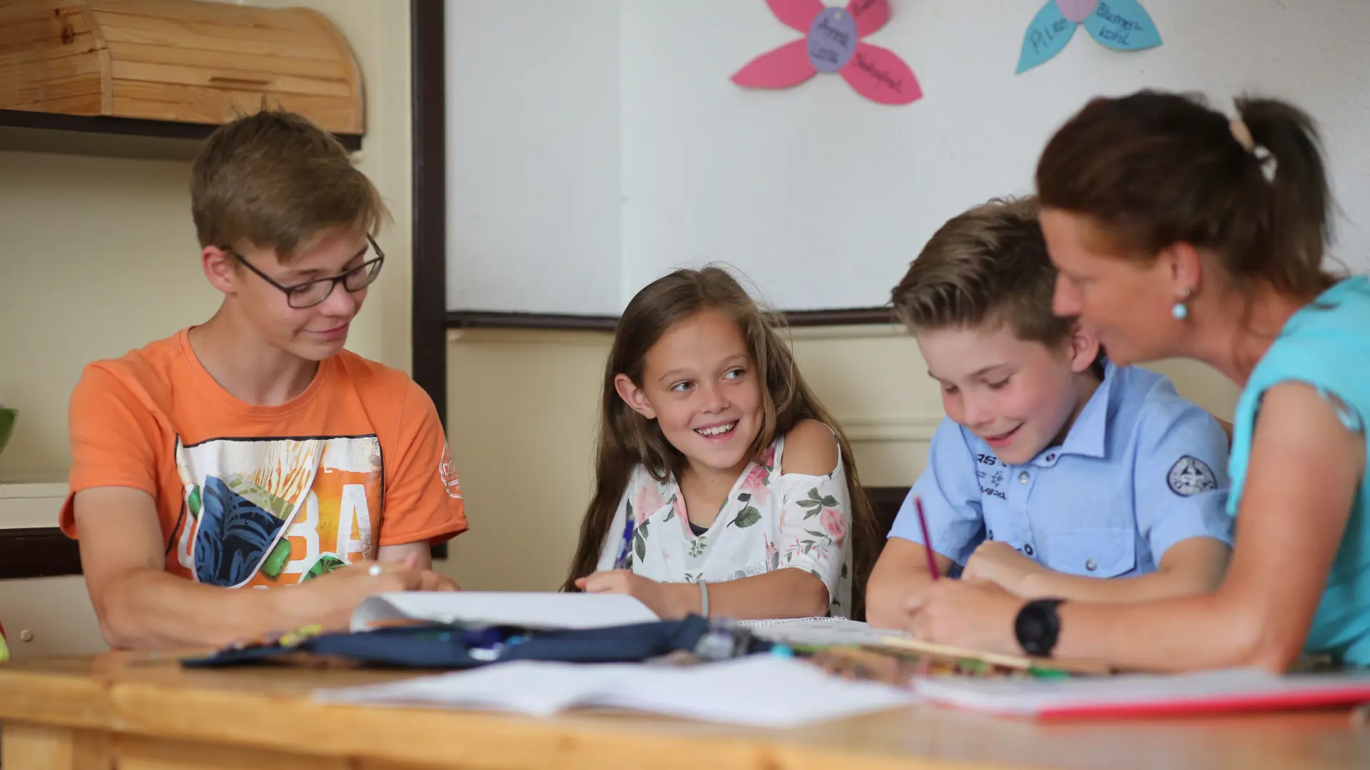 Erzieherin sitzt mit drei Kindern am Tisch zusammen
