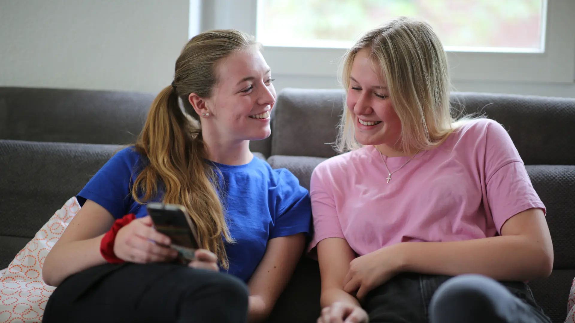zwei junge Frauen auf der Couch mit Handy