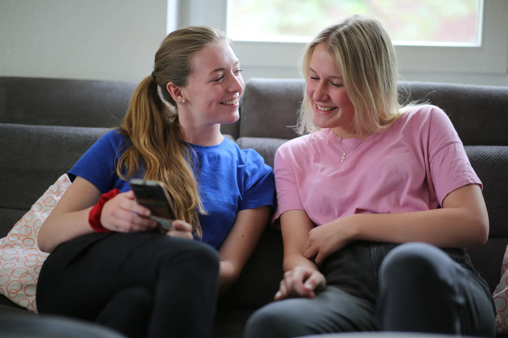 zwei junge Frauen auf der Couch mit Handy