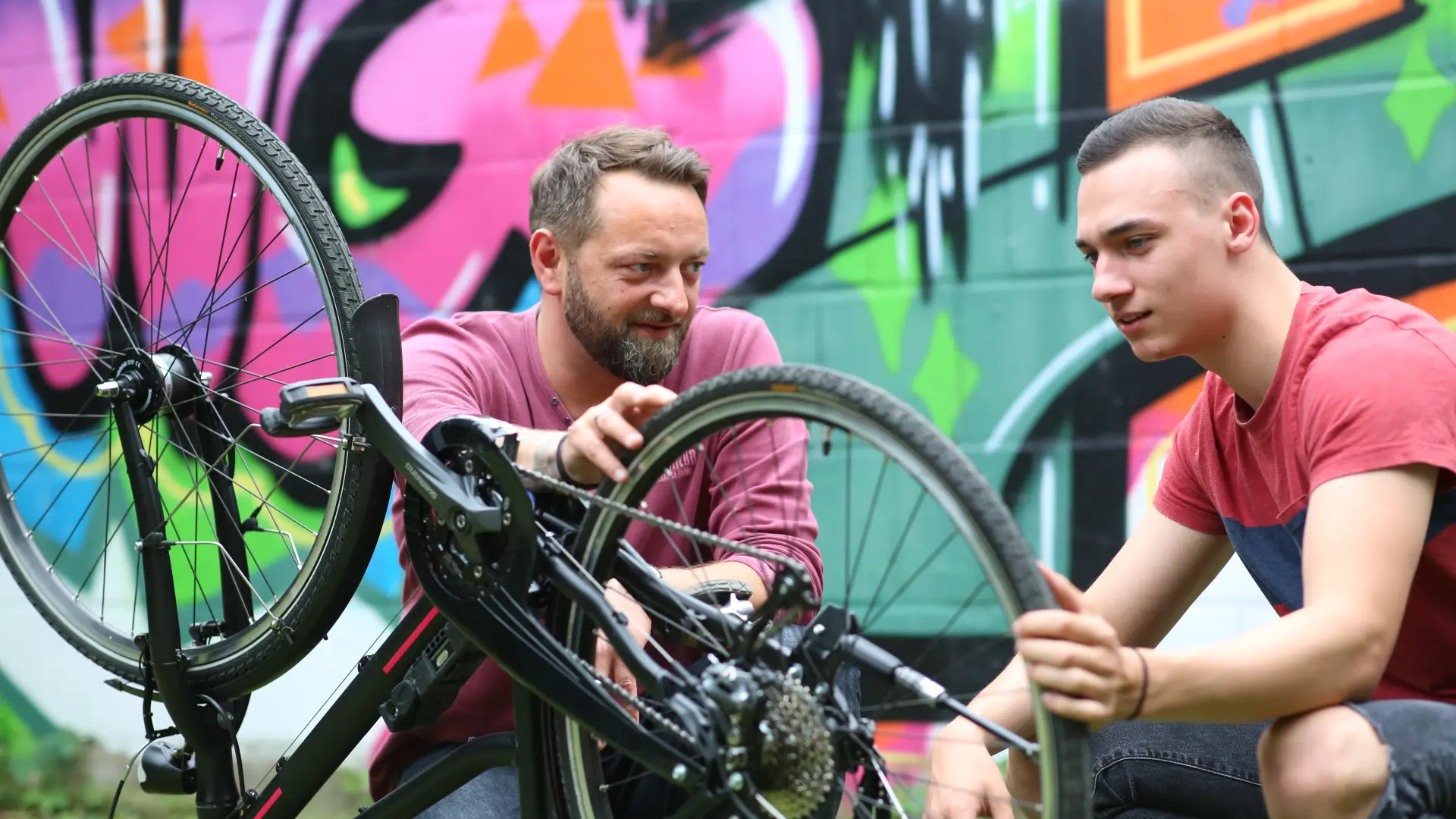 Erzieher repariert mit männlichem Teenager ein Fahrrad
