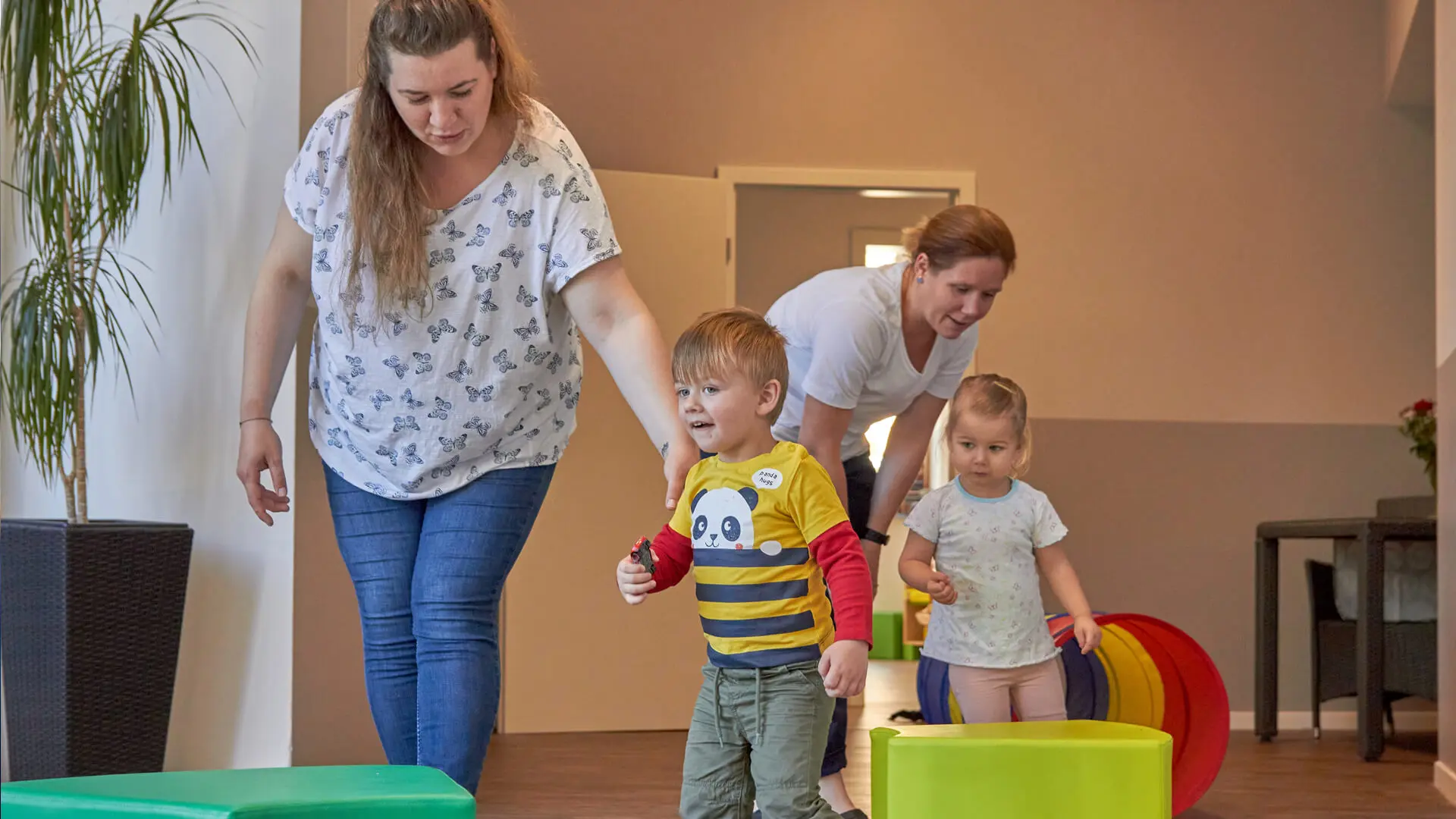 zwei Erzieherinnen mit zwei Kleinkindern im Spielebereich