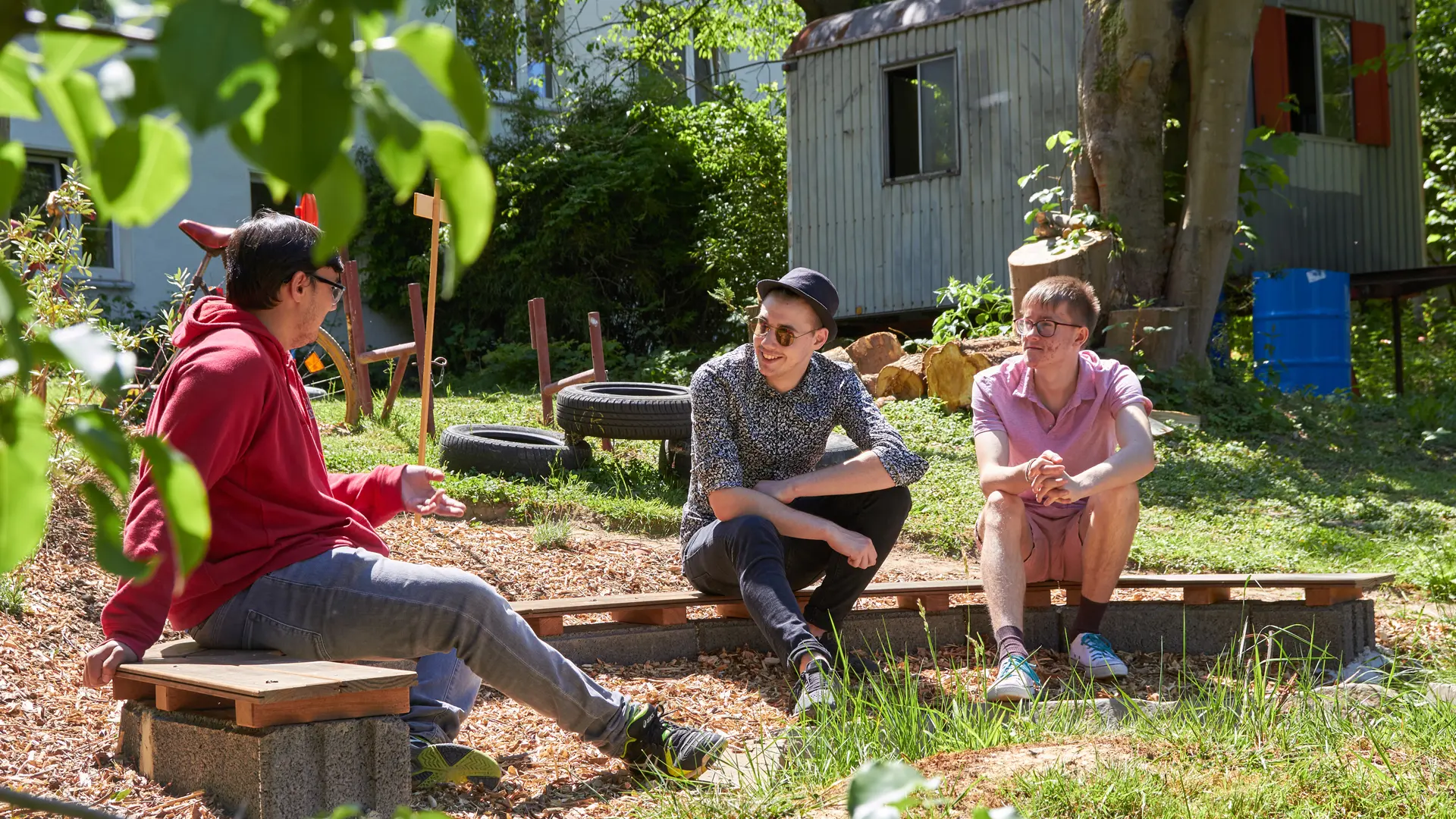 drei männliche Teenager sitzen im Garten zusammen