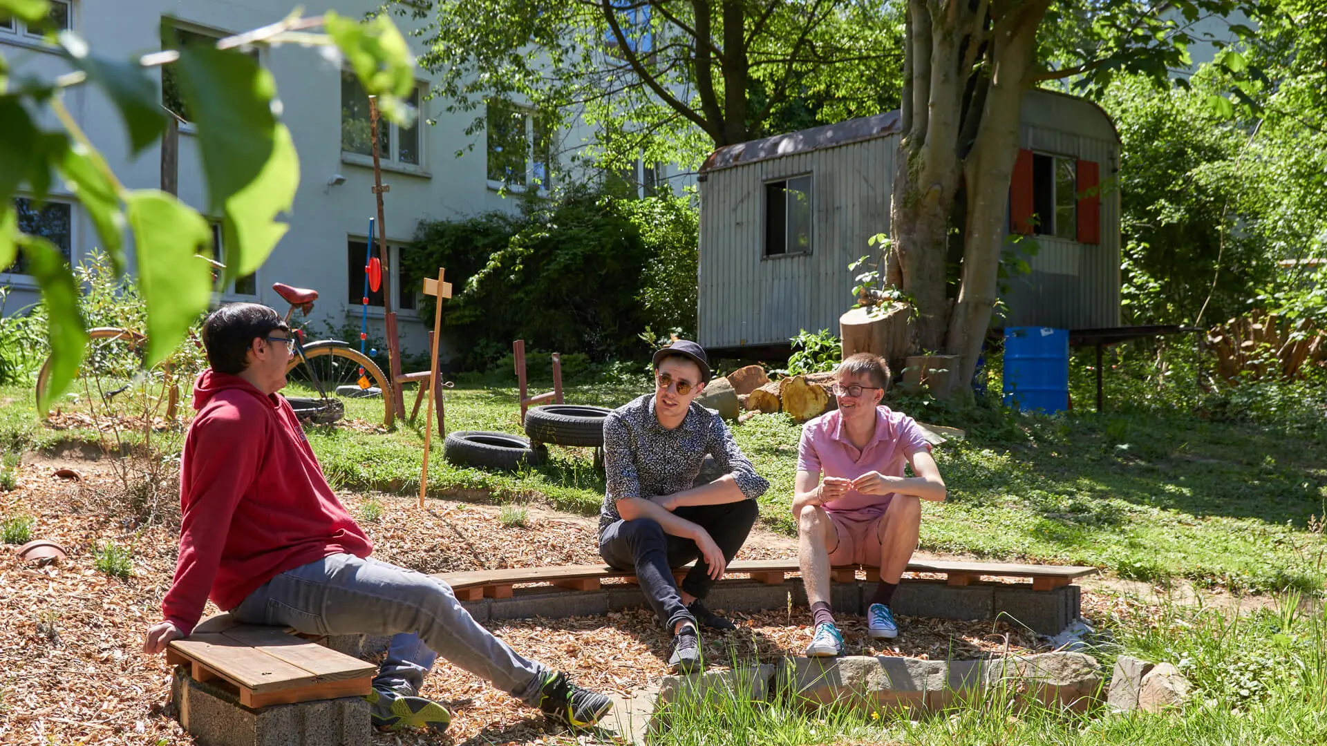 drei männliche Teenager sitzen im Garten zusammen
