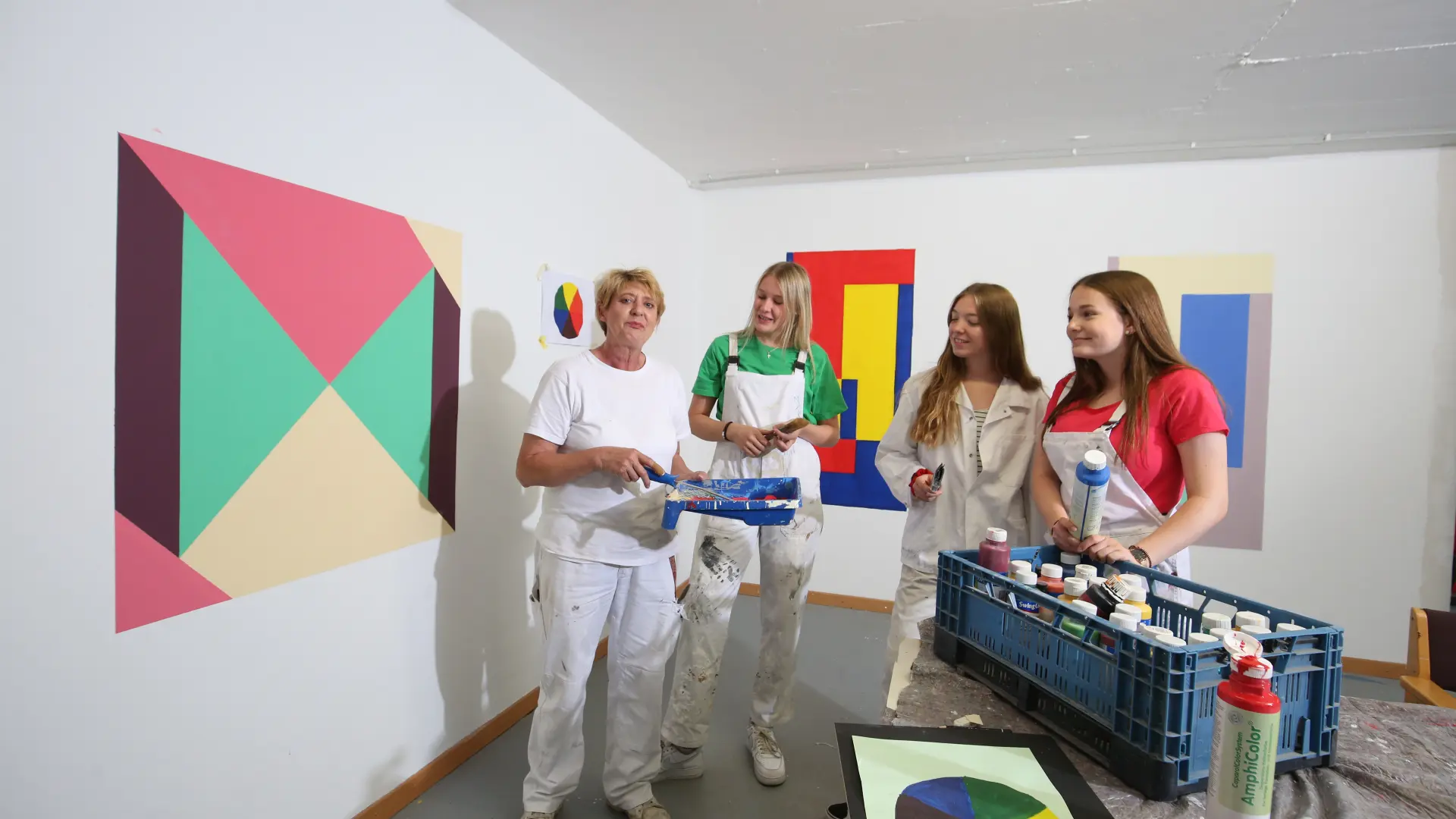 Eine Frau arbeitet mit 3 jungen Mädchen an einem Bild