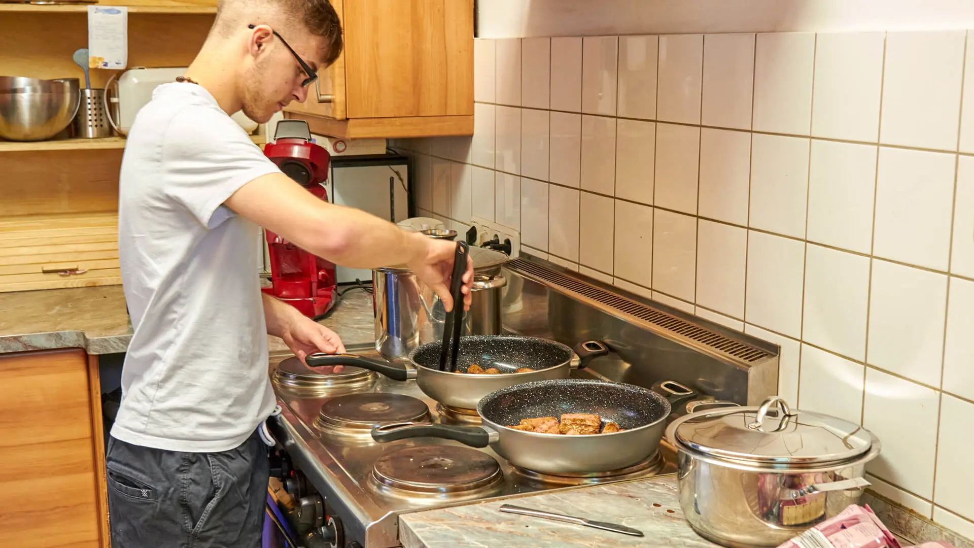Jugendlicher steht am Herd und kocht