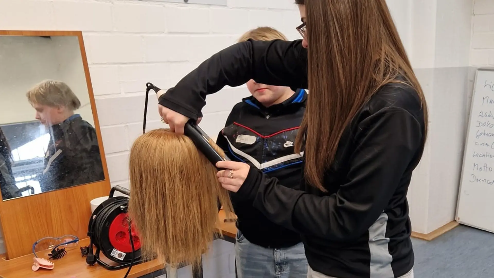 Schülerinnen frisieren Kopfhaar an einer Puppe