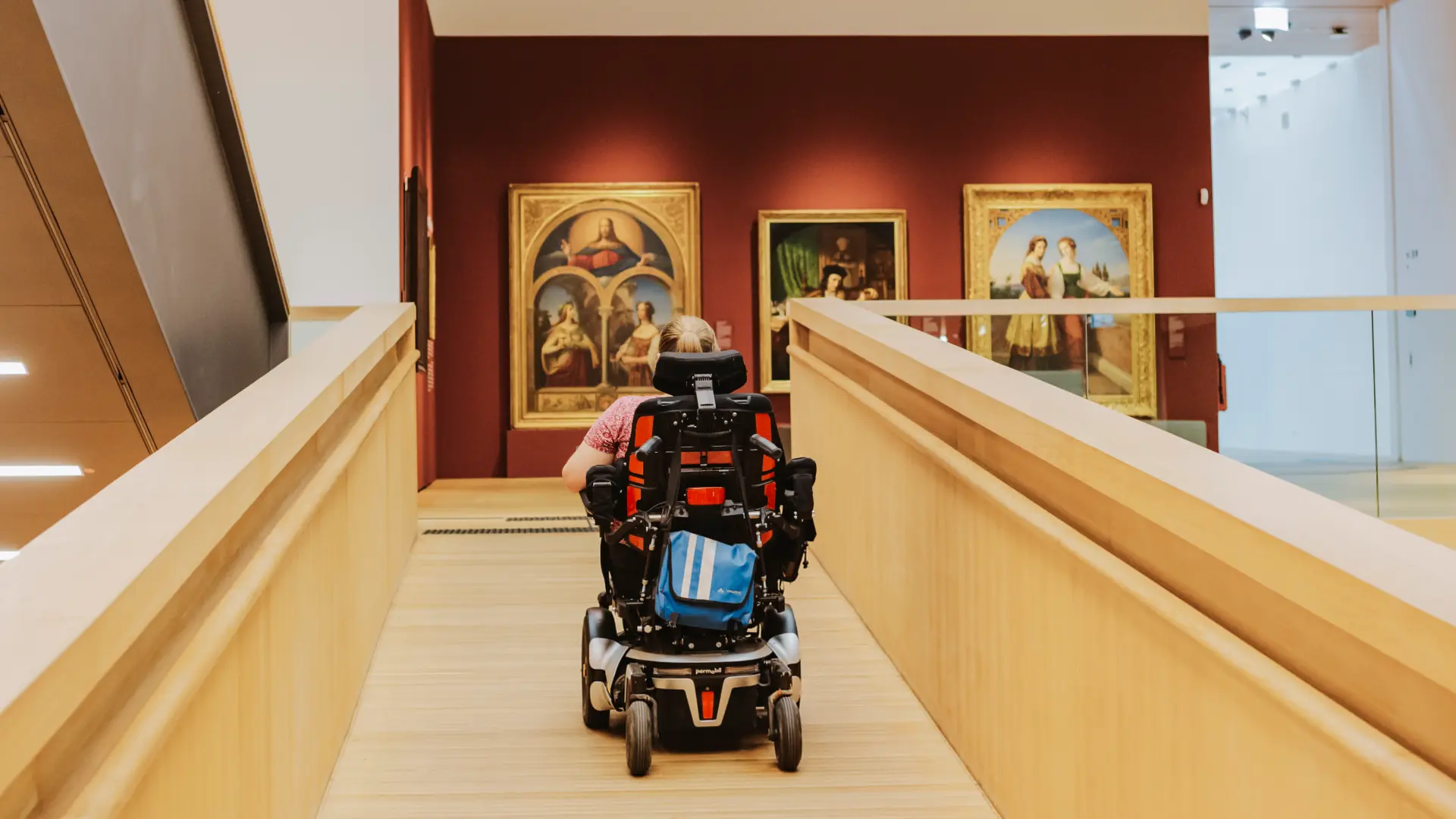 Eine Person im Rollstuhl fährt die Rampe ins zweite Obergeschoss des Landesmuseums hoch.