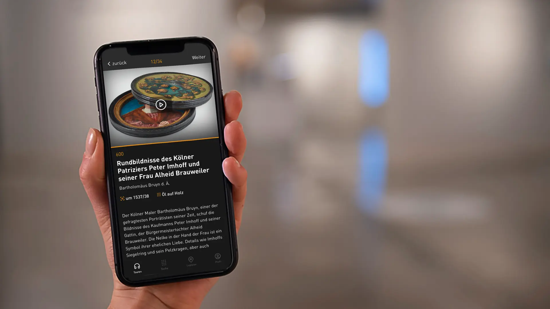Eine Hand hält ein Smartphone mit einer Infoseite aus dem Mediaguide. Darauf sind Fotos und ein erklärender Text zu sehen.