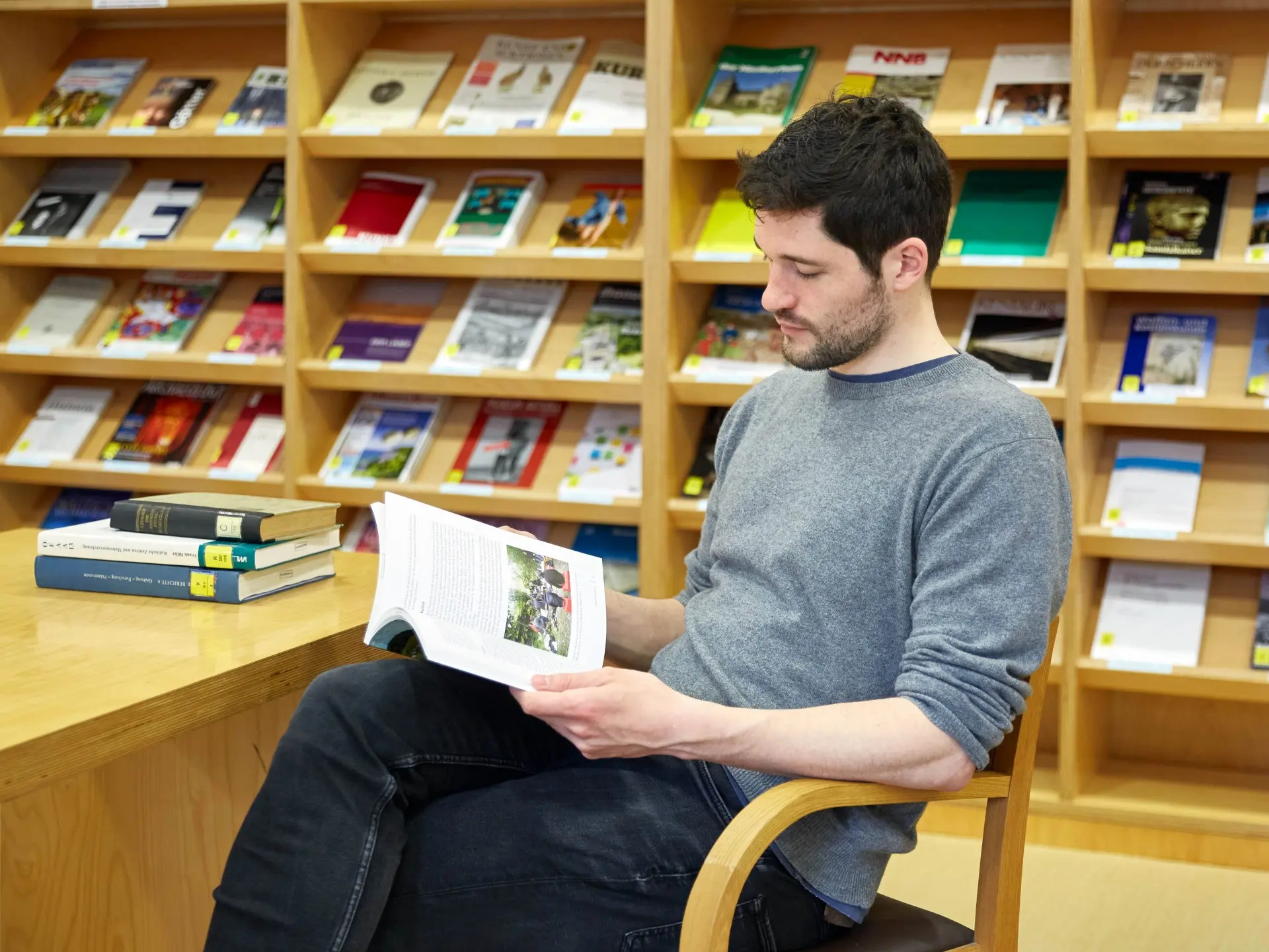 Ein Mann liest an einem Bibliotheksschreibtisch in einem Buch.