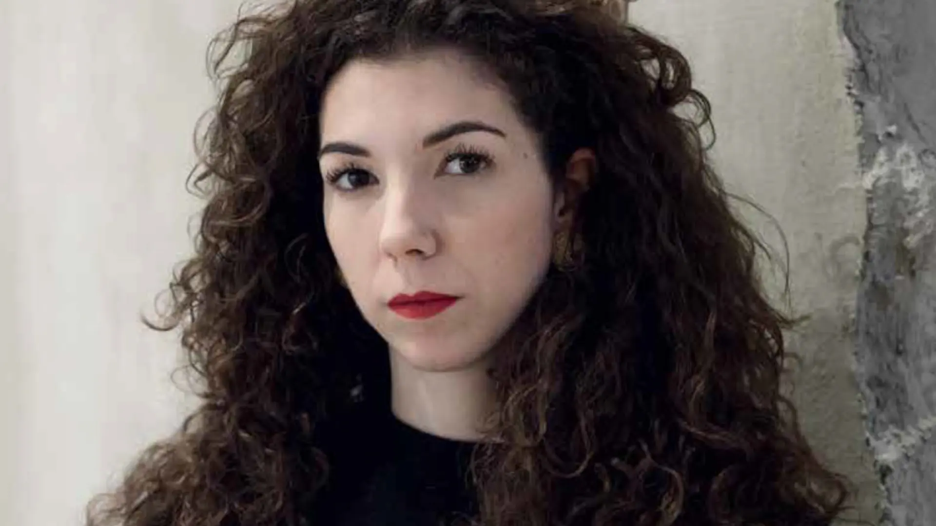 Ein Porträt einer jungen Frau mit dunklen Locken.