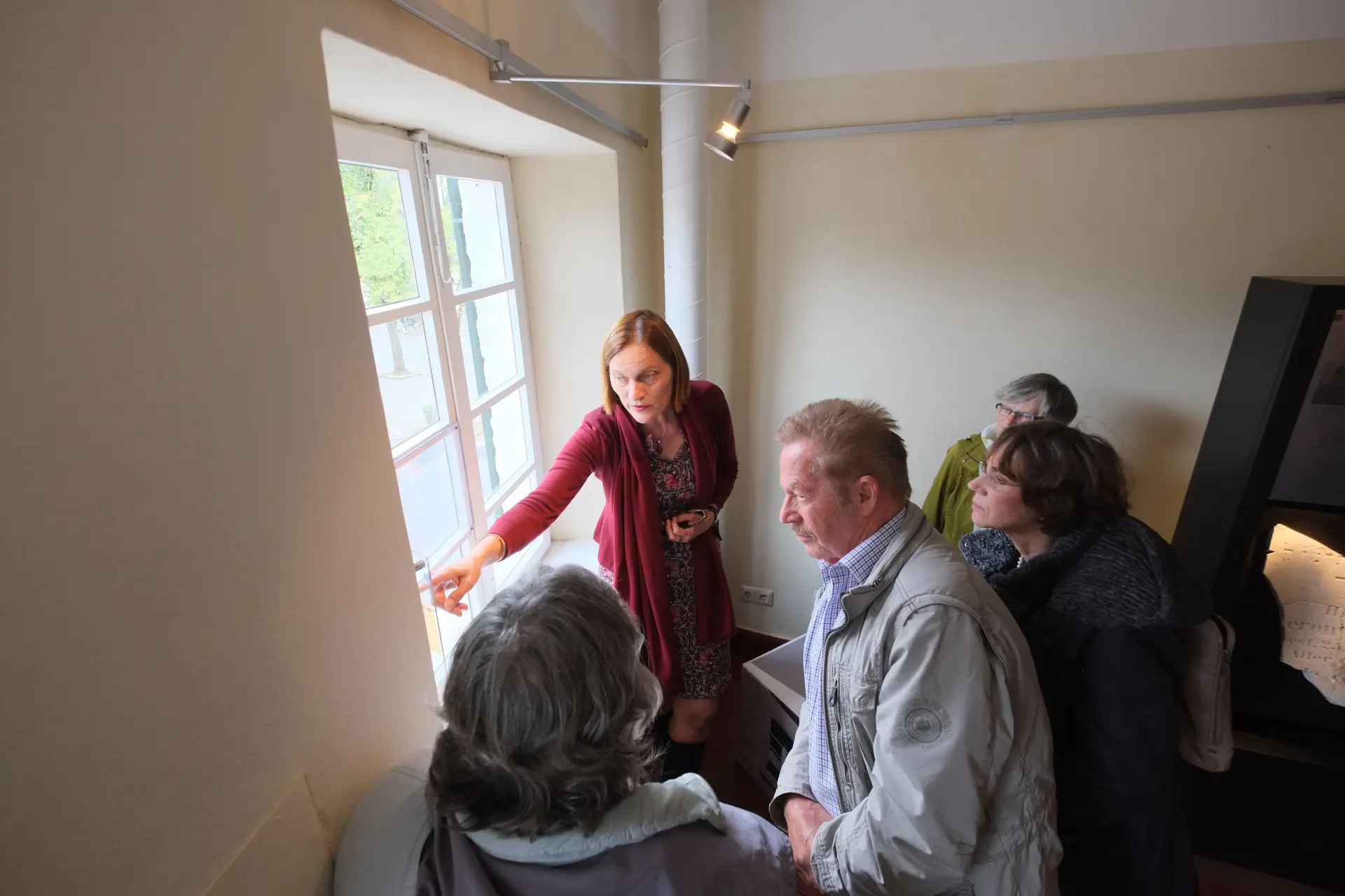 Eine Frau zeigt während einer Führung in der Ausstellung auf eine Inschrift auf einem Fenster.