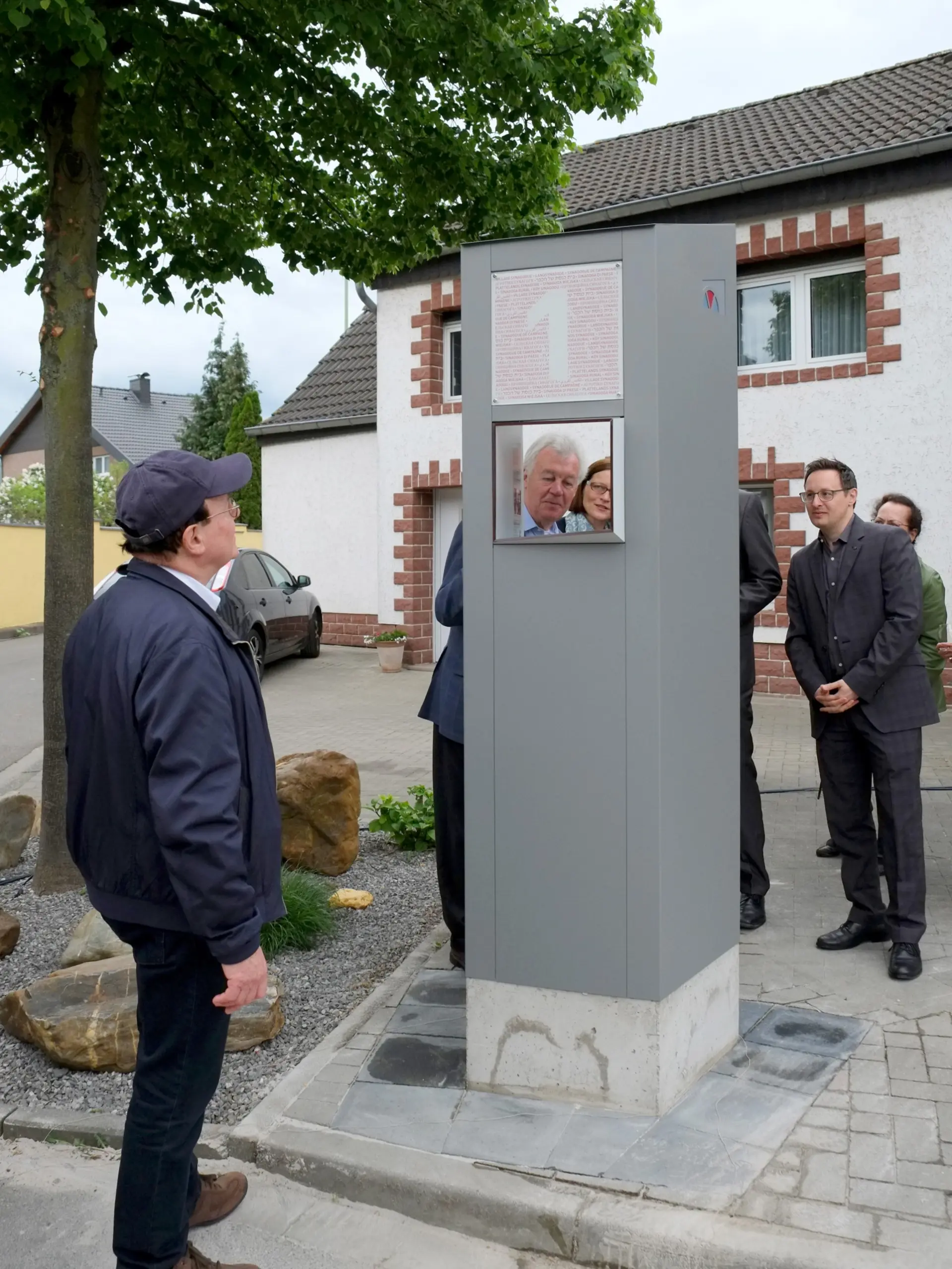 Mehrere Personen betrachten eine graue Stele mit Durchguck.