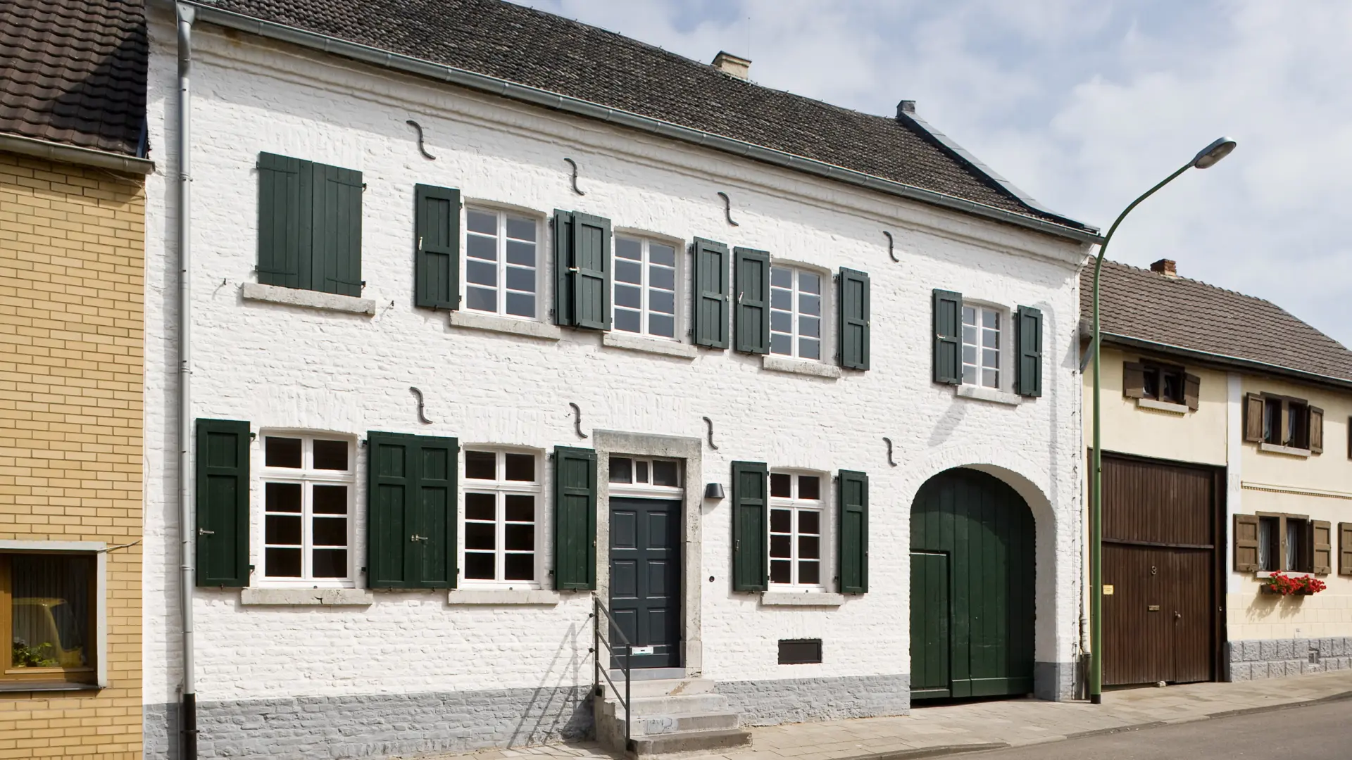 Zehn Personen posieren für ein Foto auf Treppenstufen vor dem Eingang zu einem weiß getünchten Wohnhaus.