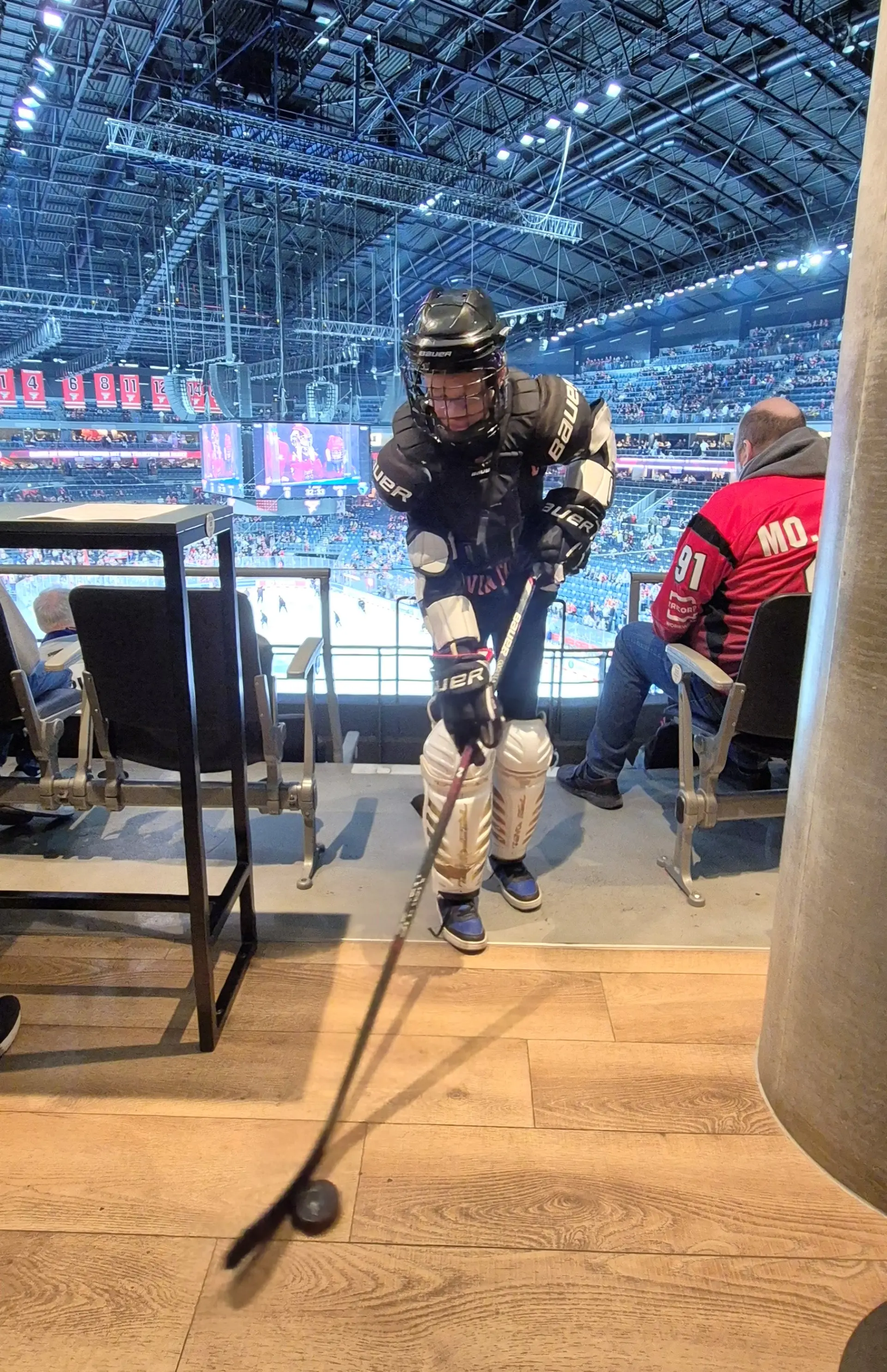 Ein Schüler in Eishockeymontur mit Schläger und Puck.
