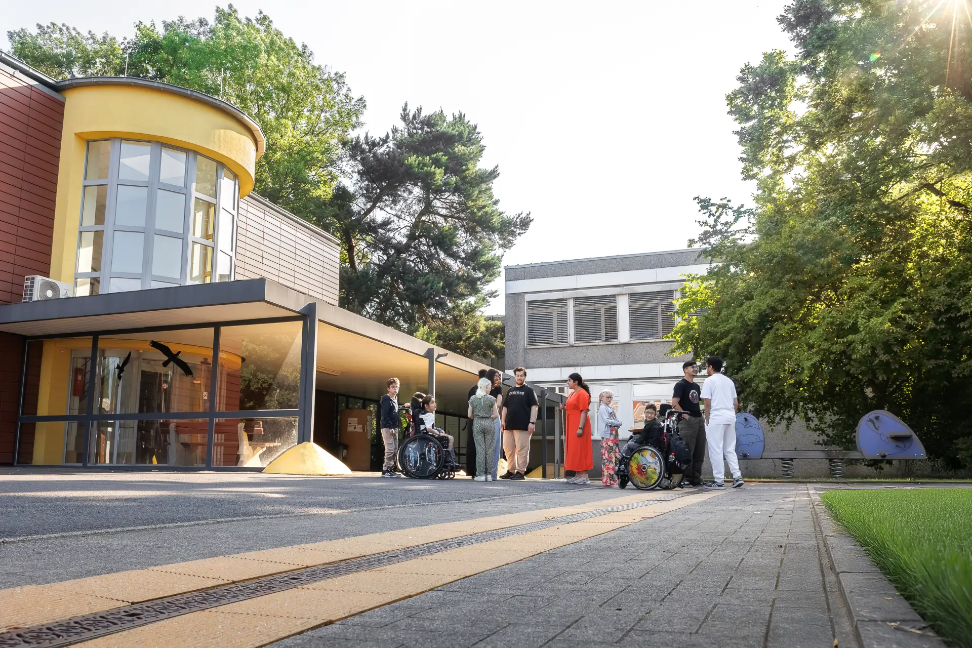 Foto vom Außengelände der Schule mit Blick auf die neue Schule. Im Vordergrund spielen Schüler*innen der verschiedenen Stufen.